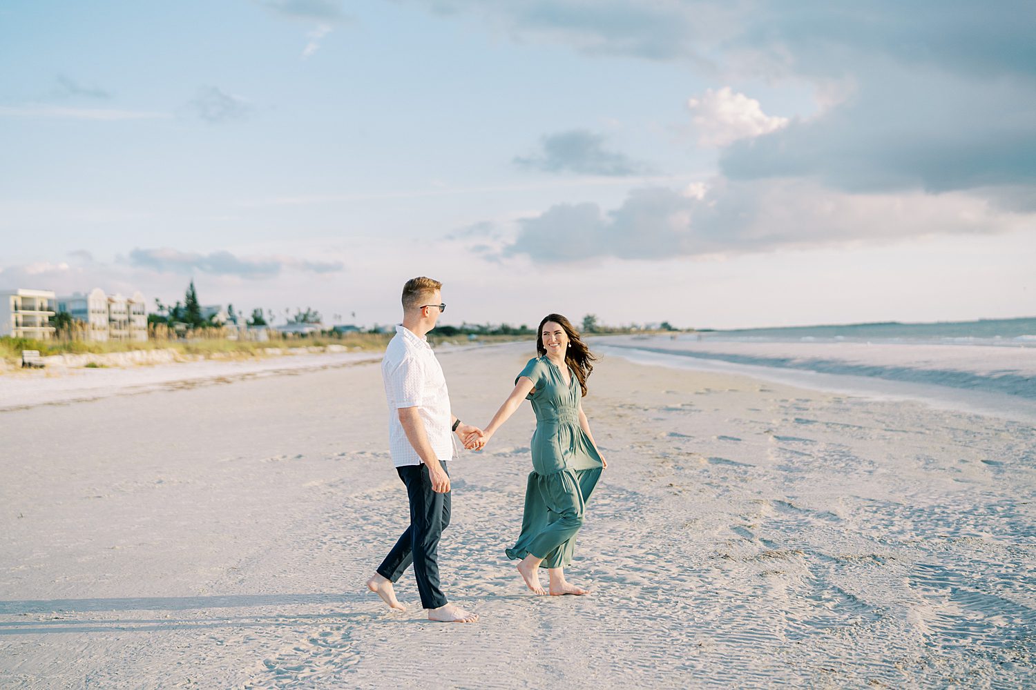 woman in green dress leads fiancee across beach in Tampa FL