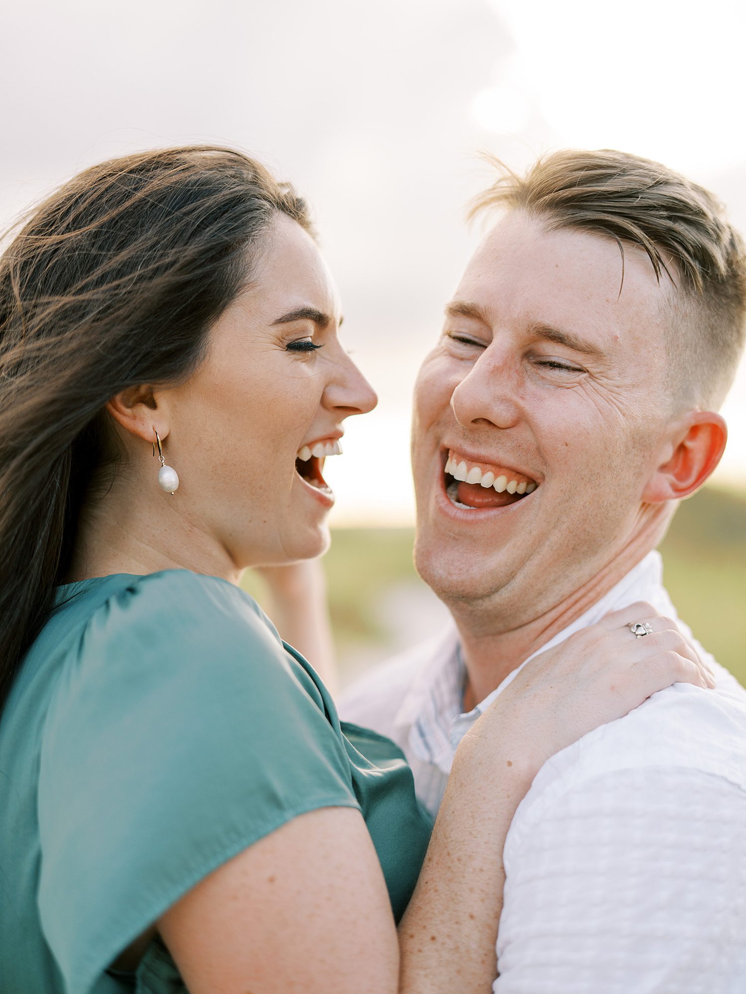 man and woman laugh during engagement photos on Tampa beach 