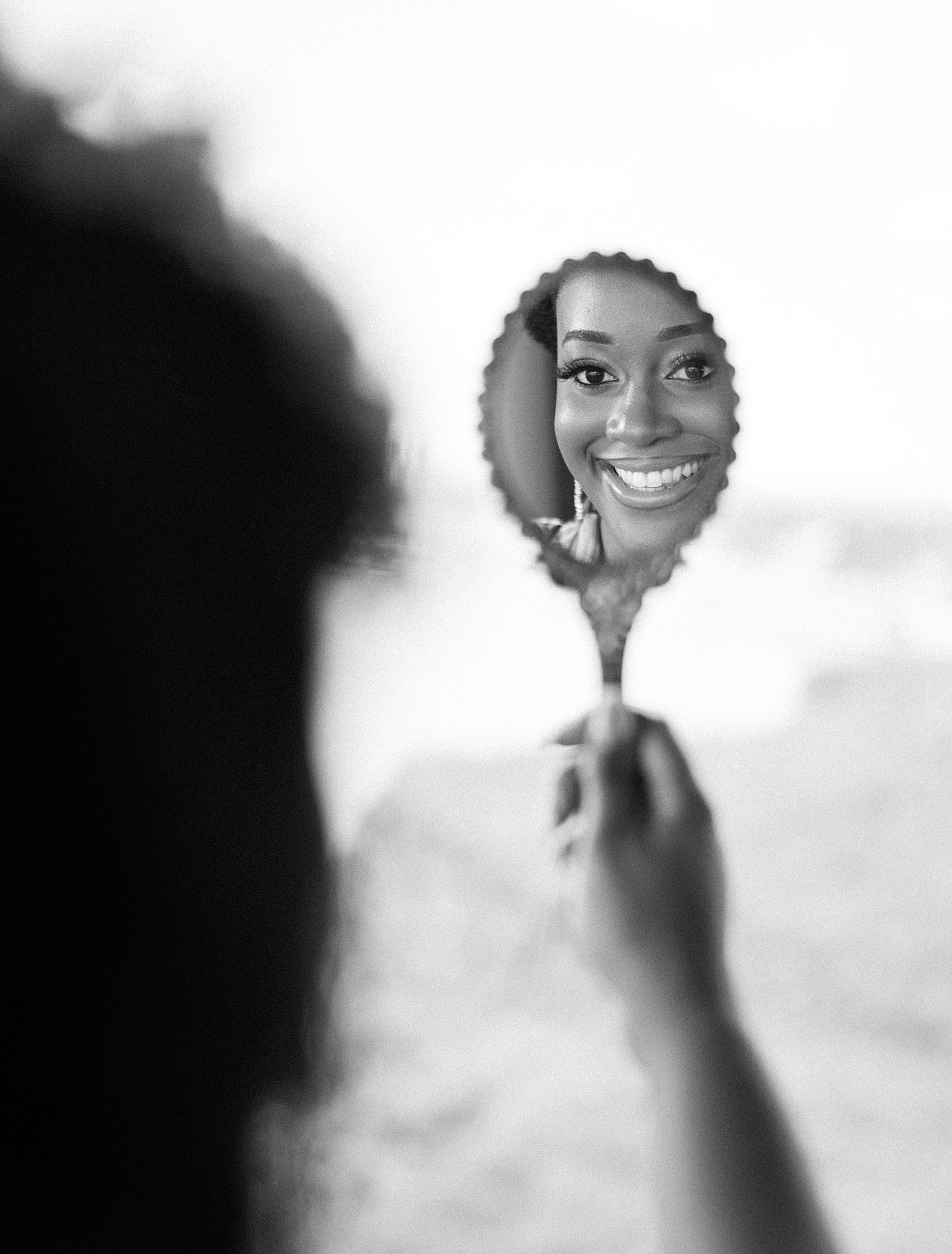 black woman holds up mirror and smiles into it 