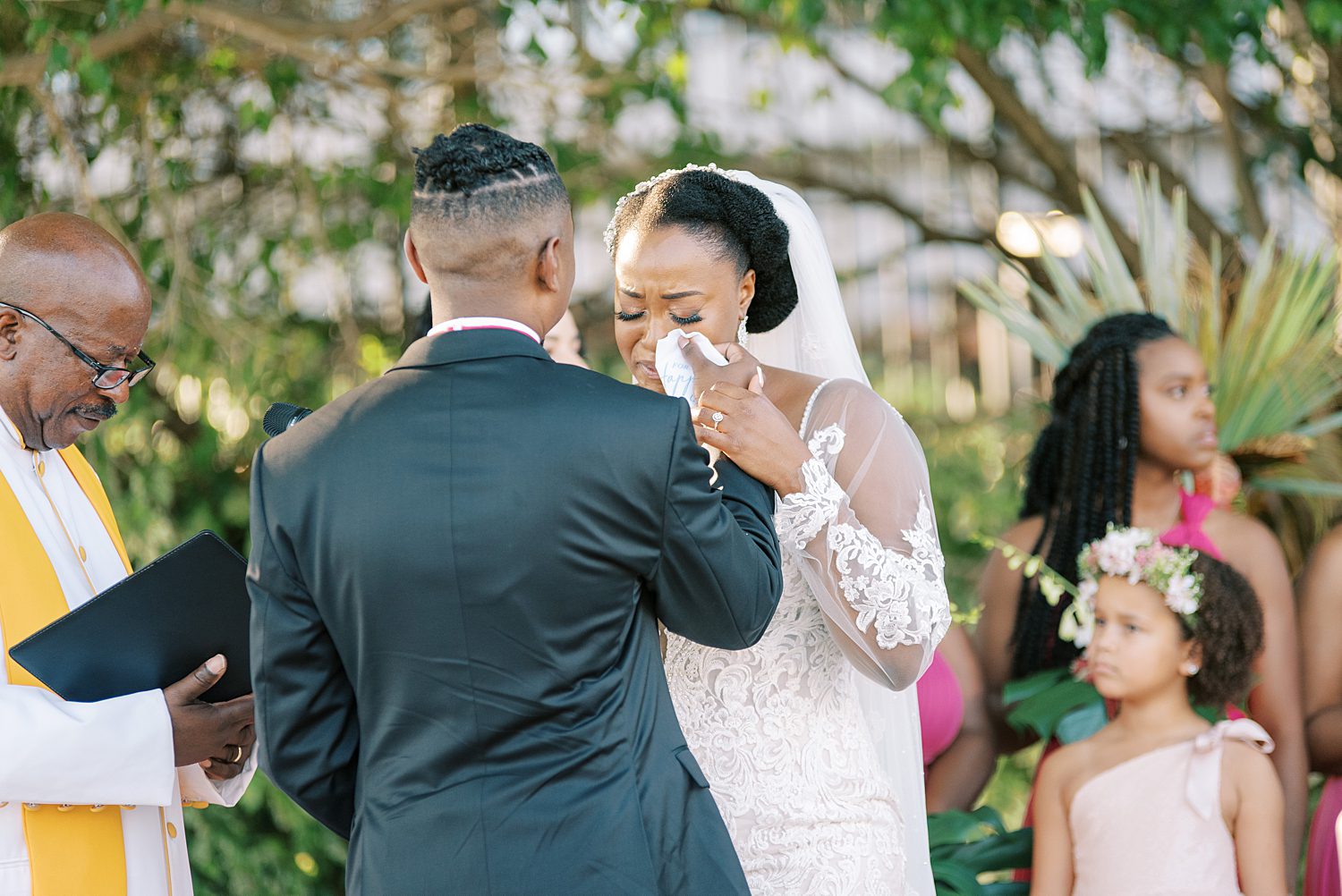 bride cries and groom helps wipe tears from her face during ceremony 