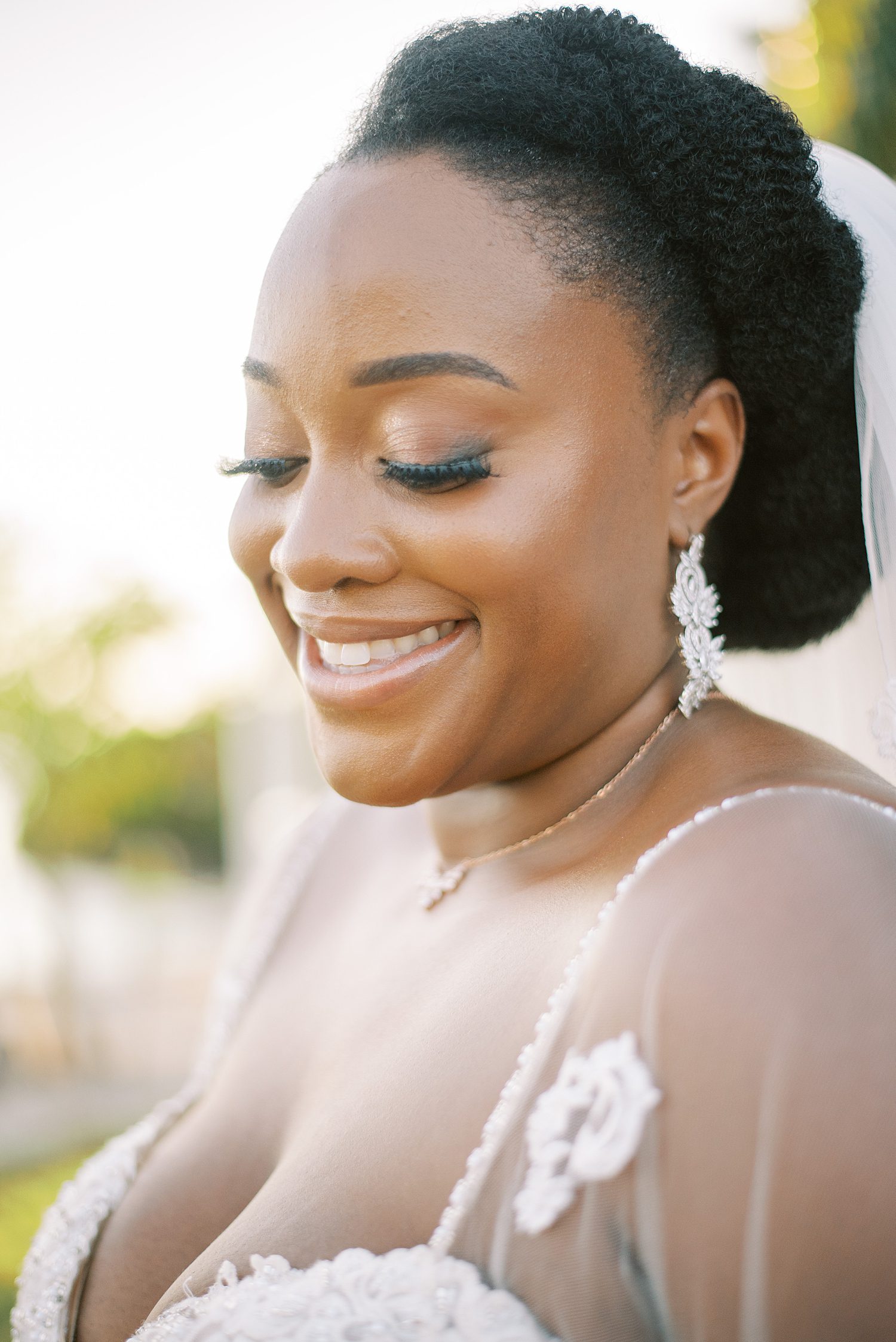 bride looks down showing off eye shadow and dangling earrings 