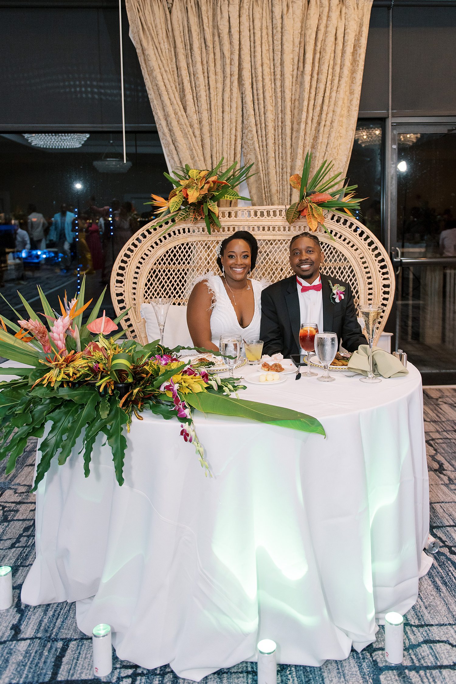 bride and groom sit at sweetheart table with wicked chair and tropical plants at The Rusty Pelican Tampa