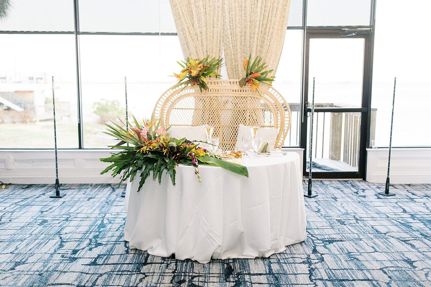 sweetheart table with wicker chair and tropical plants on edge of table 