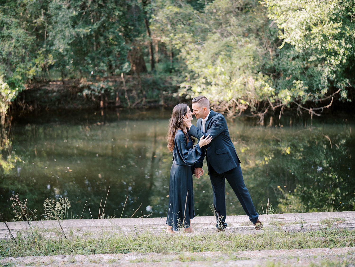 man leans to kiss woman in teal dress during Hillsborough River State Park engagement session