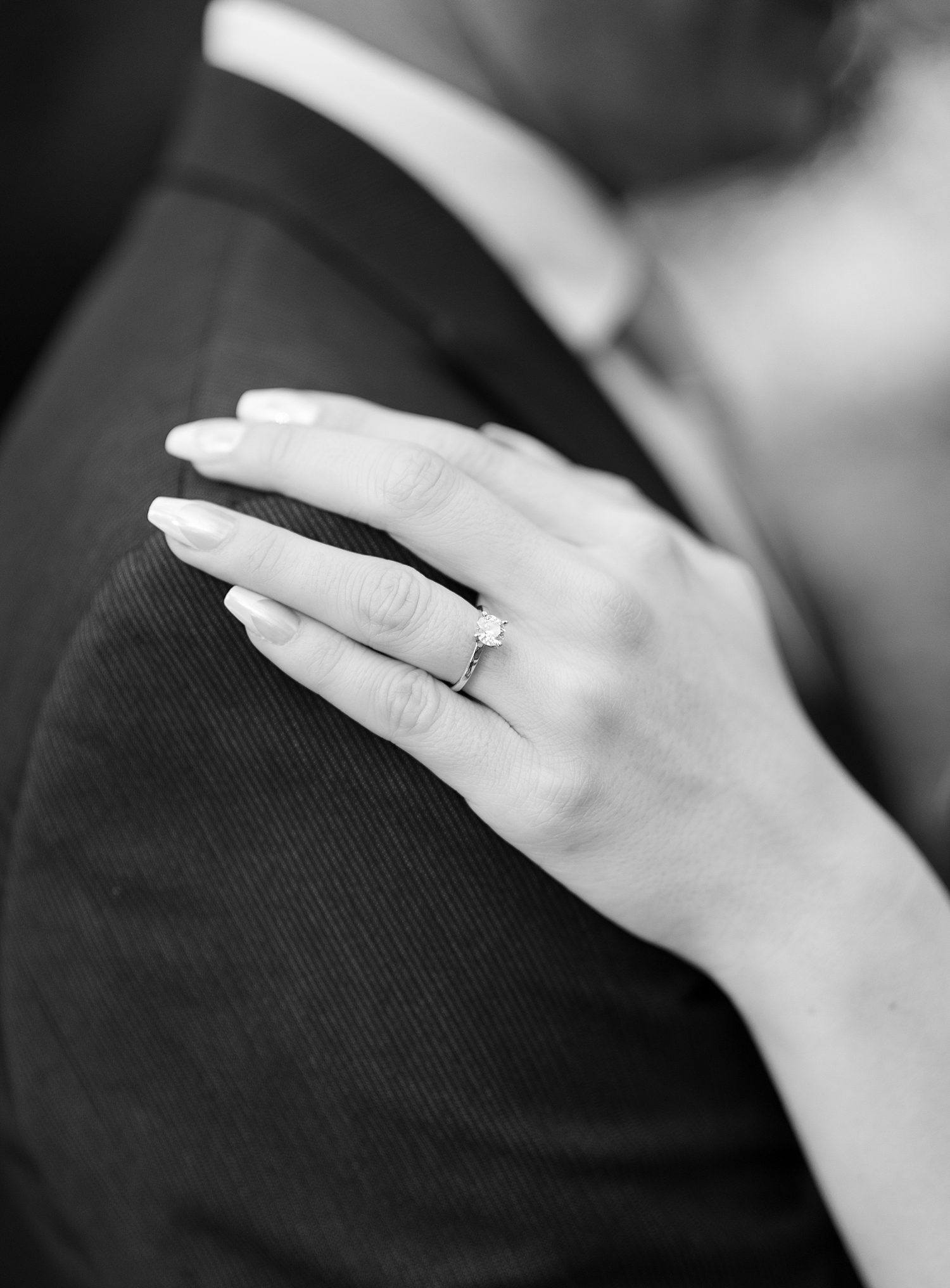 woman lays hand on shoulder of groom showing off engagement ring 