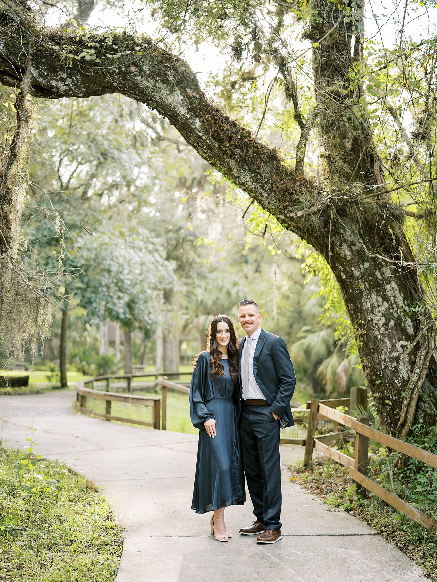 woman in teal dress holds man's arm during Tampa engagement session 