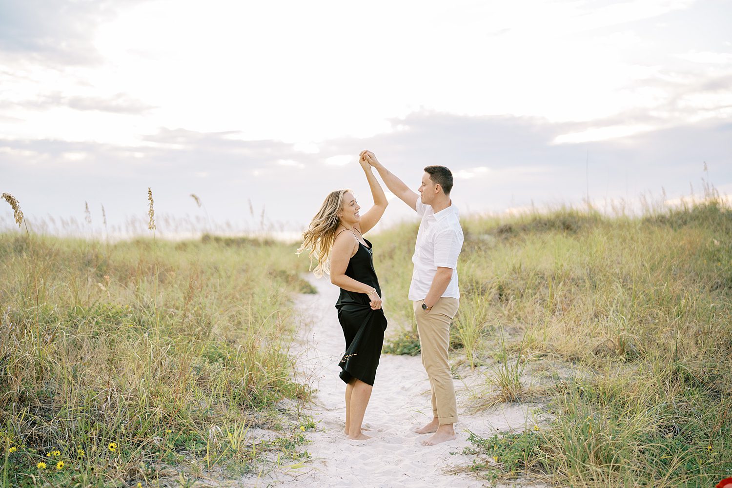 groom twirls bride on sand dunes in Tampa FL