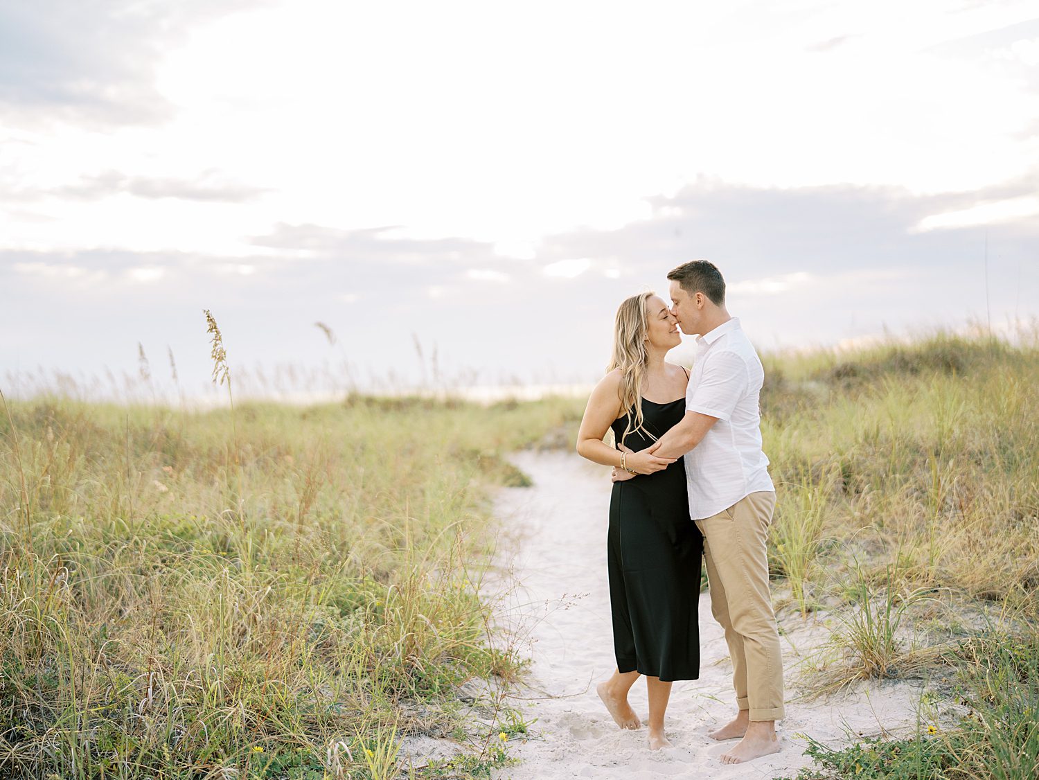 engaged couple hugs and kisses on sand dues in Tampa FL