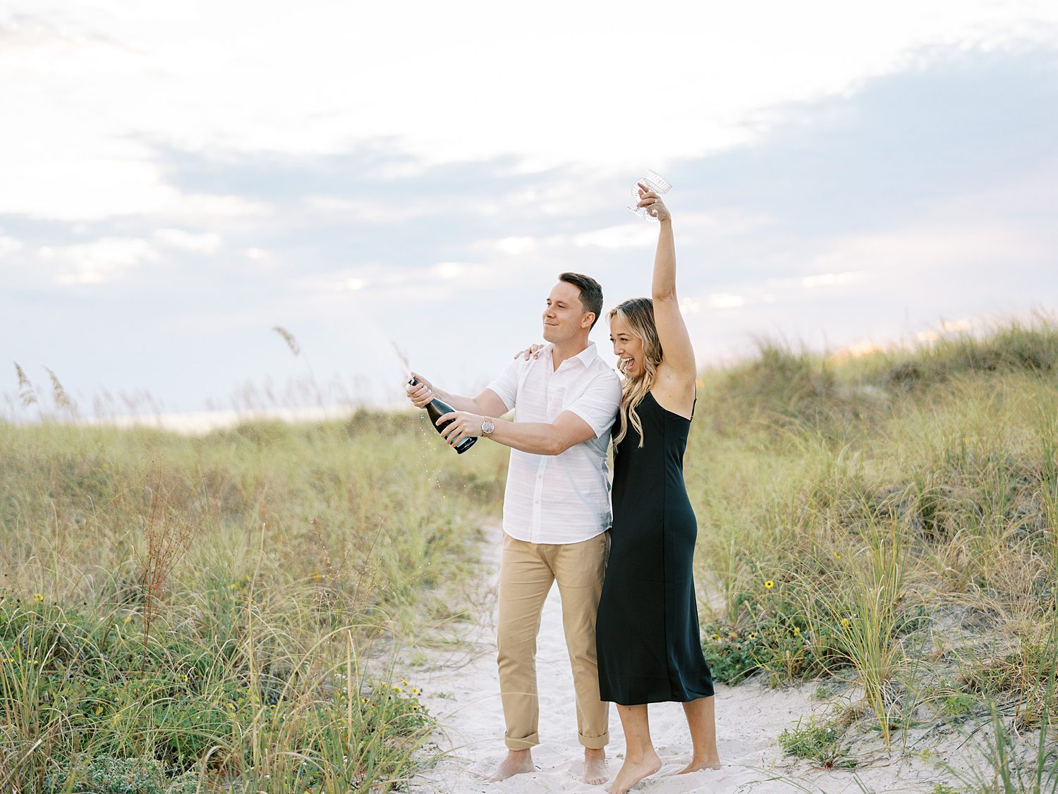 couple cheers and pops champagne during Tampa engagement session 