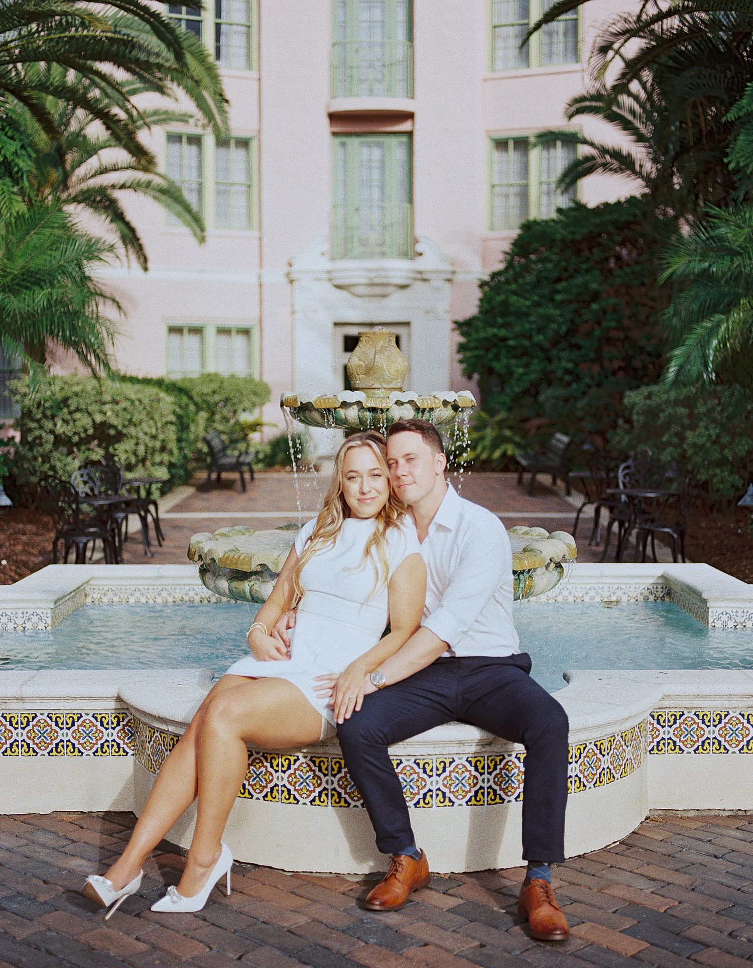 engaged couple sits on fountain in front of the Tampa Museum of Fine Arts