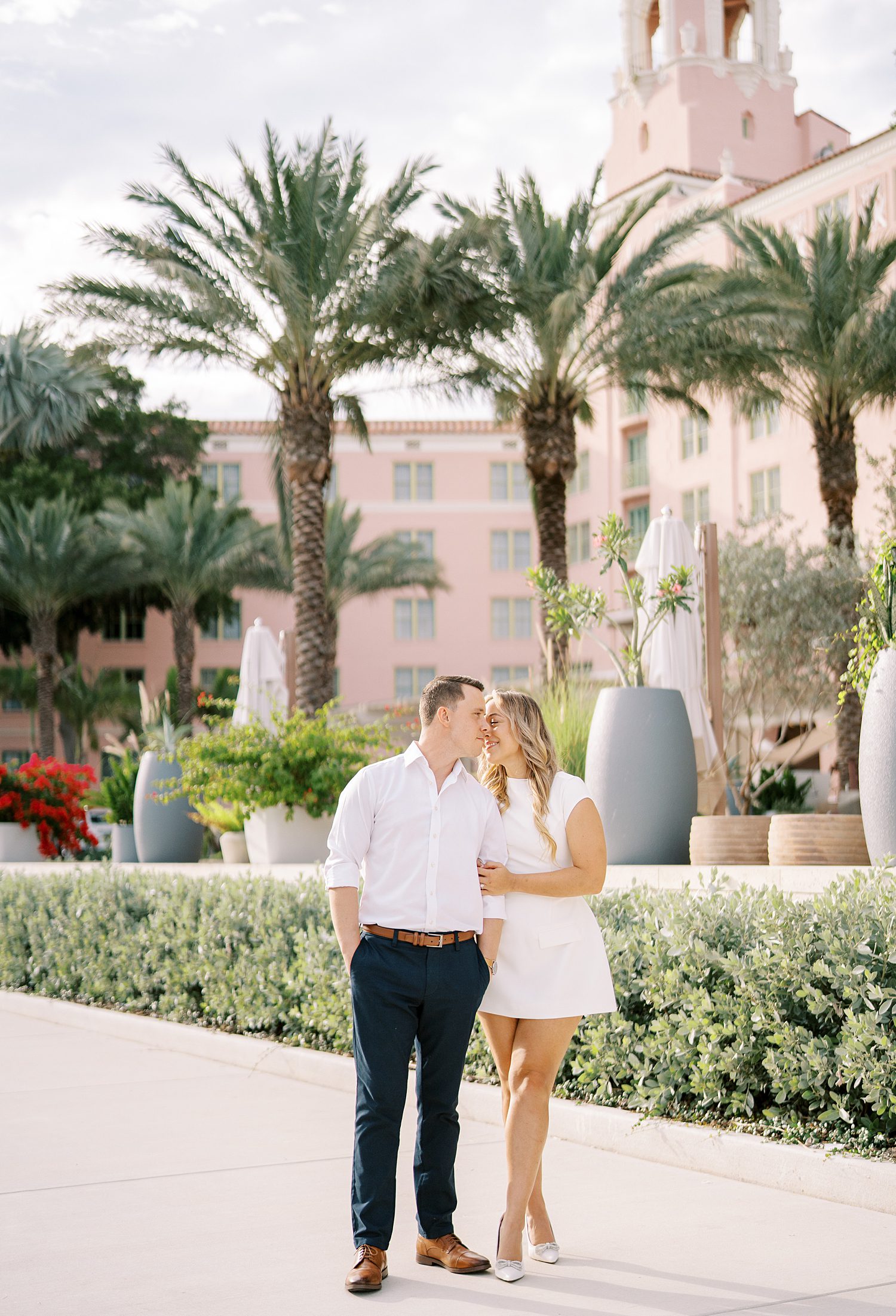 engaged couple kisses on sidewalk in front of palm trees near the Tampa Museum of Fine Arts