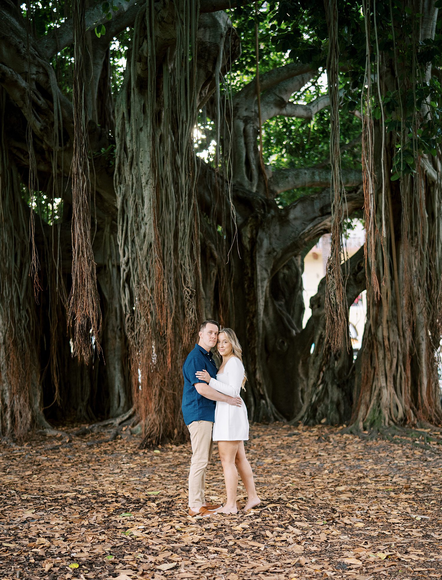 engaged couple poses in front of trees at Tampa Museum of Fine Arts