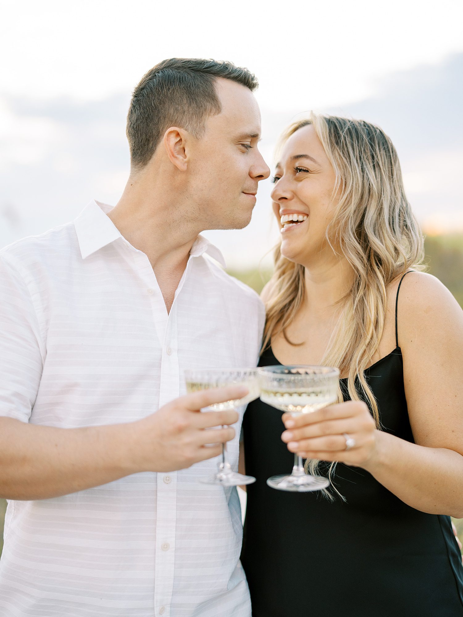engaged couple toasts champagne during beach engagement session in Tampa FL
