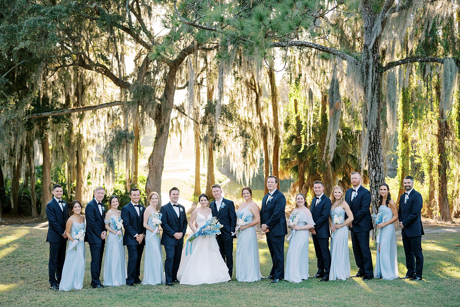 bride and groom stand with wedding party in light blue and navy attire 