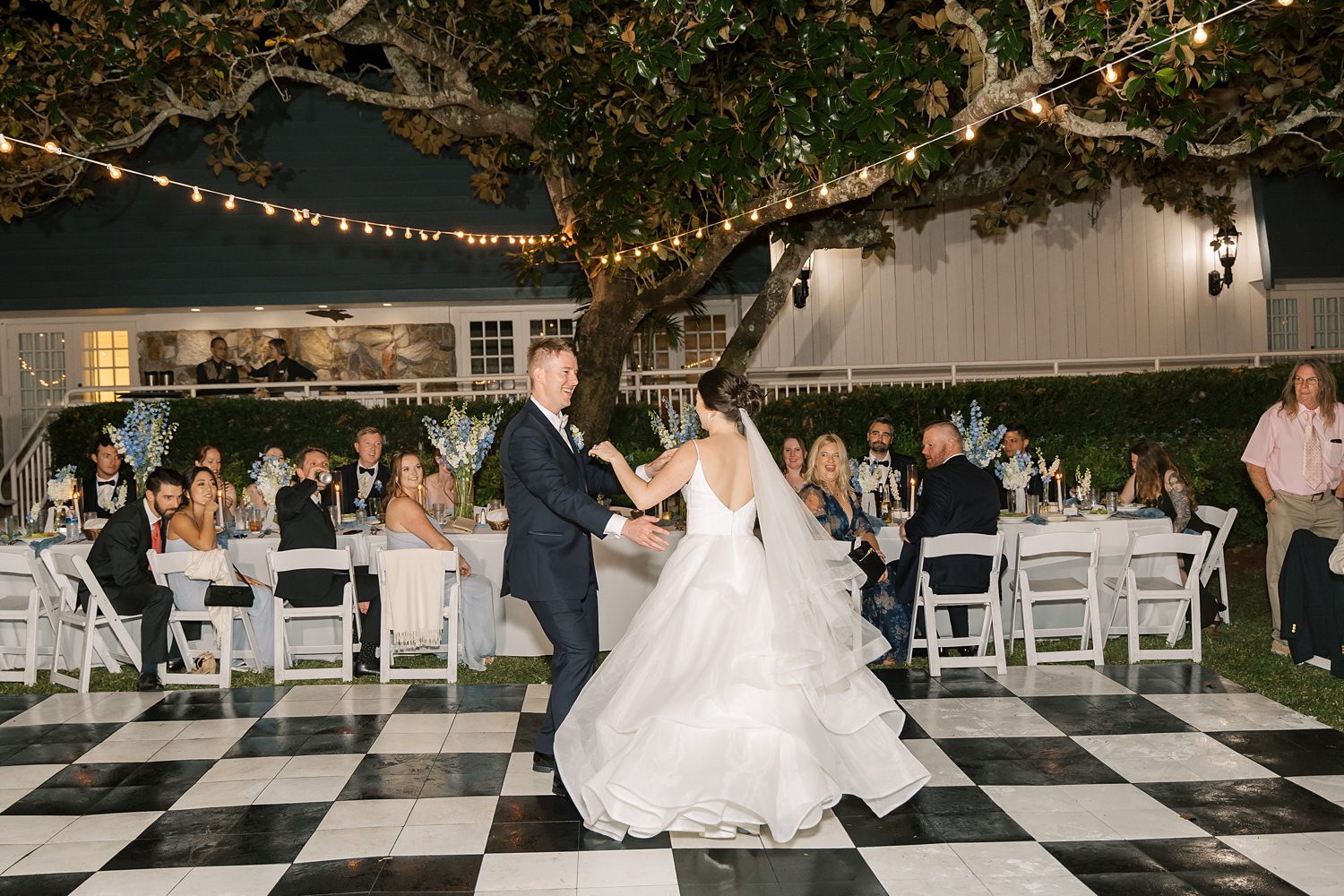 bride and groom dance on black and white dance floor during summer reception at open air reception at Innisbrook Resort