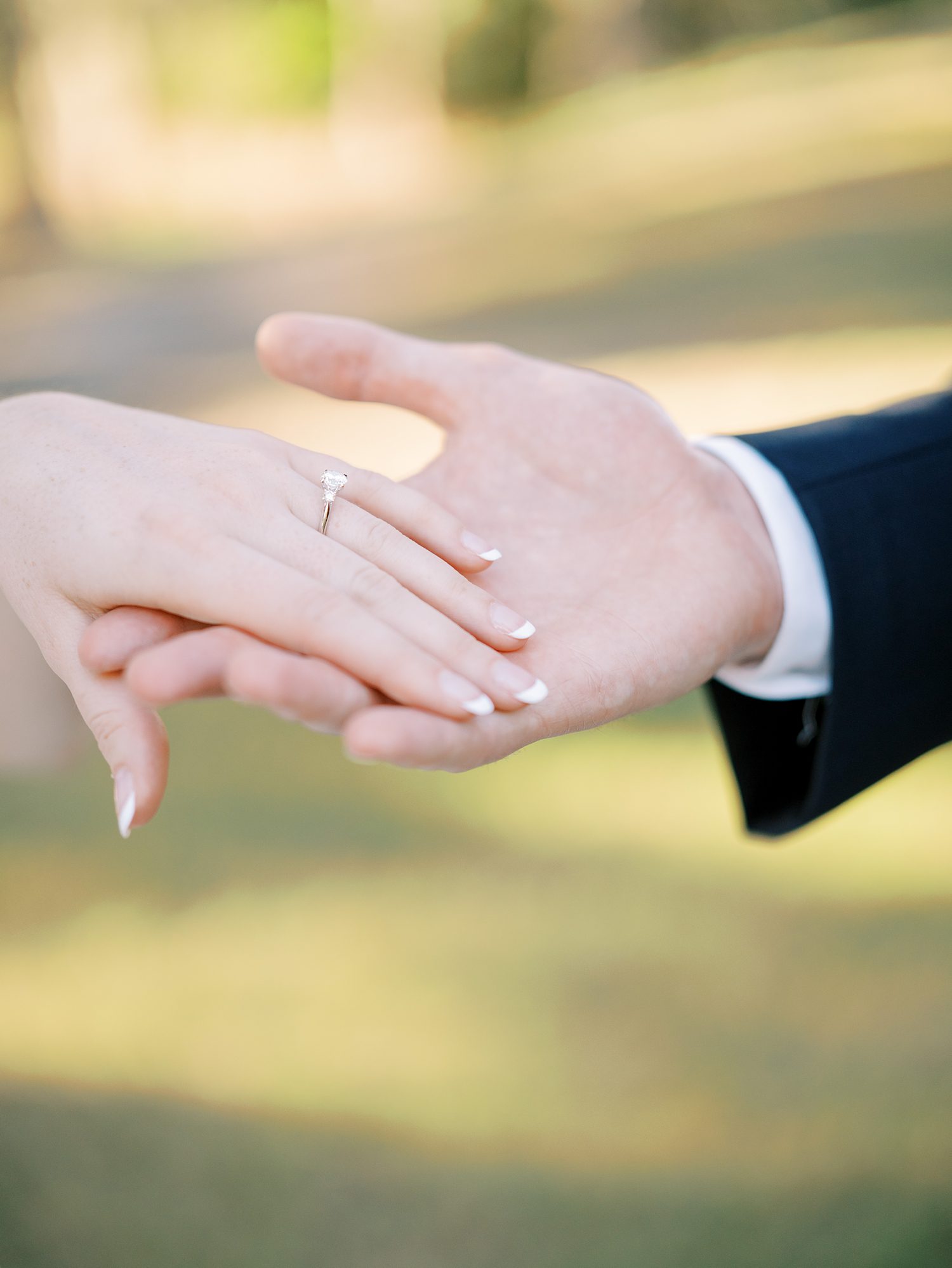 bride and groom hold hands showing off bride's engagement ring