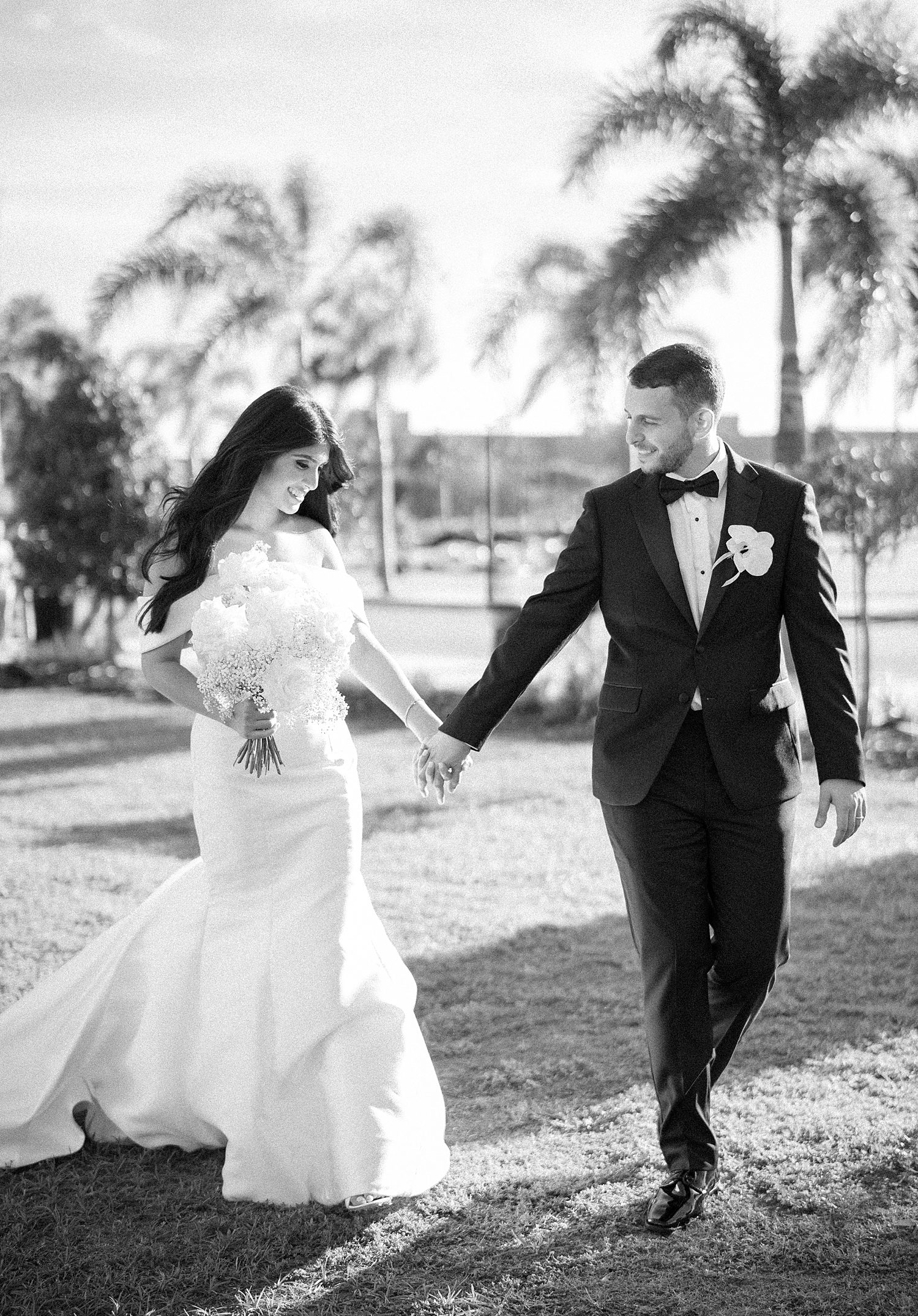 black and white portrait of bride and groom holding hands walking in Tampa FL