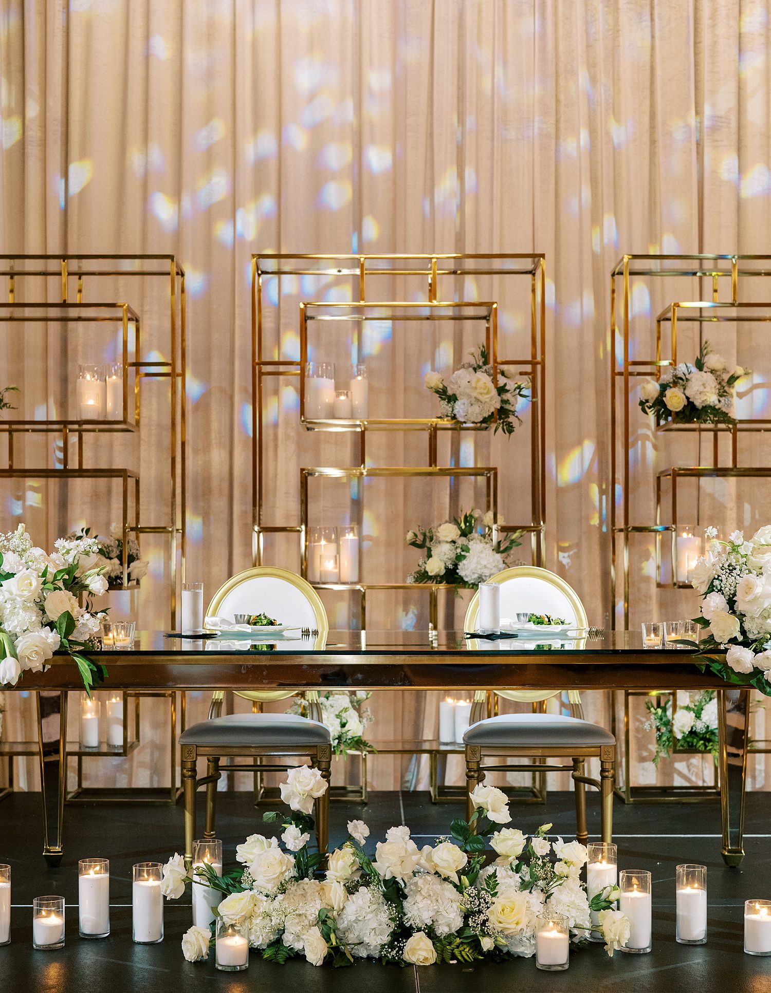 wedding reception sweetheart table in front of gold shelves at Armature Works