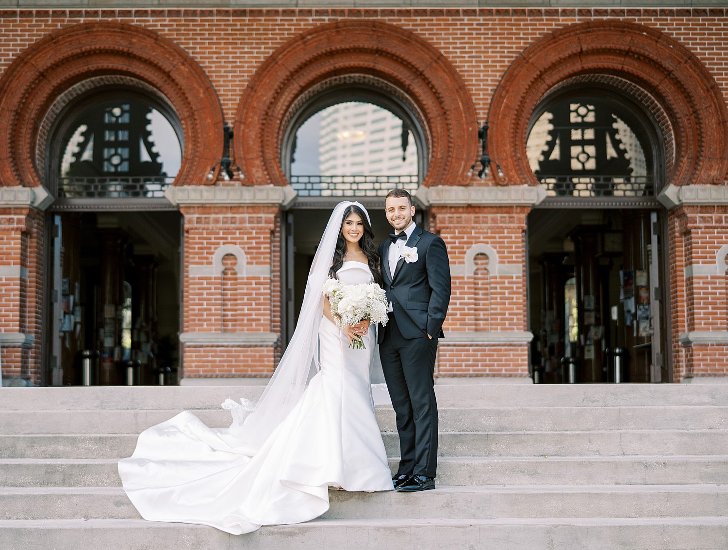 bride and groom stand on steps of Armature Works