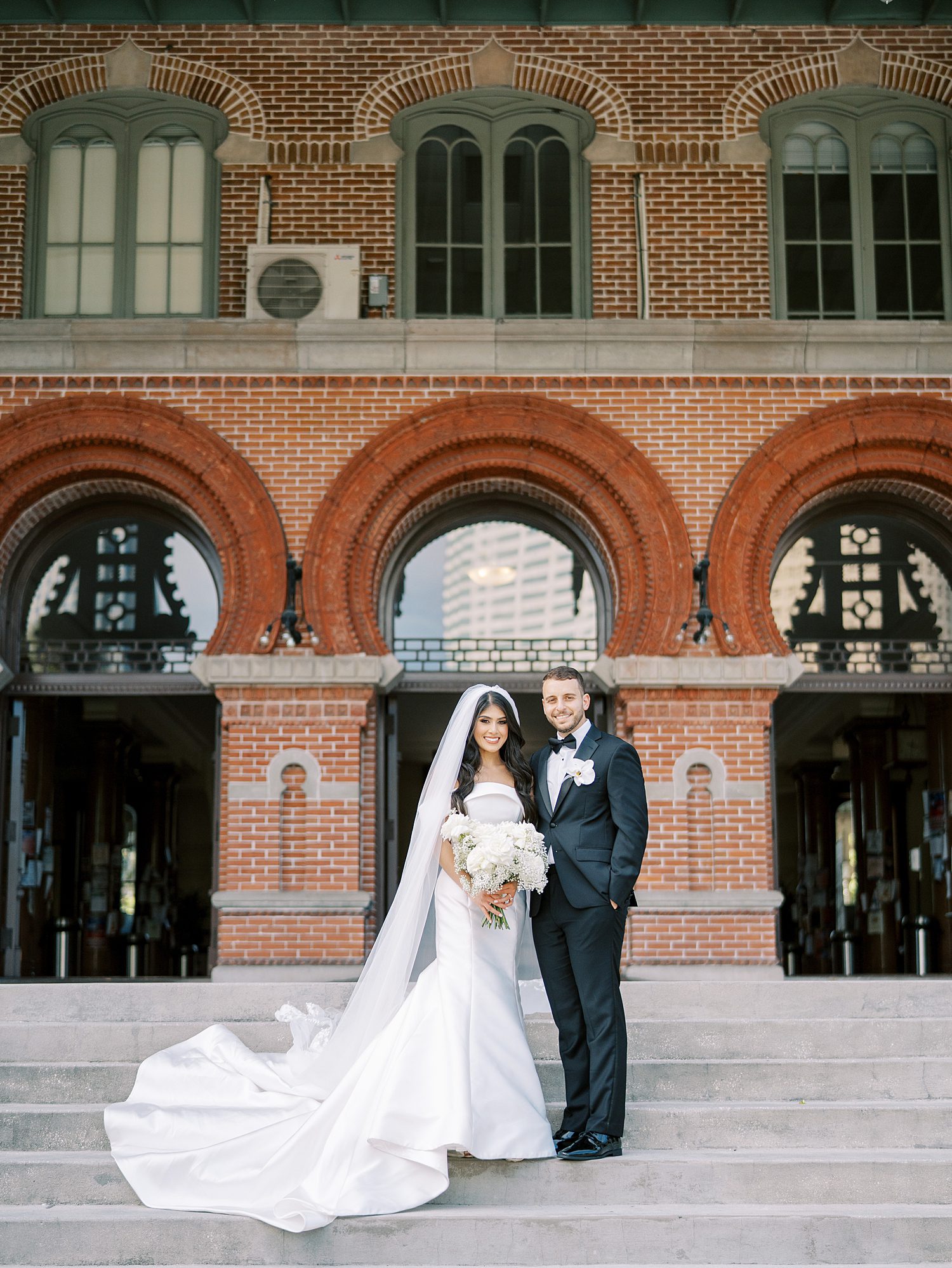 bride and groom stand on steps of Armature Works building in Tampa FL