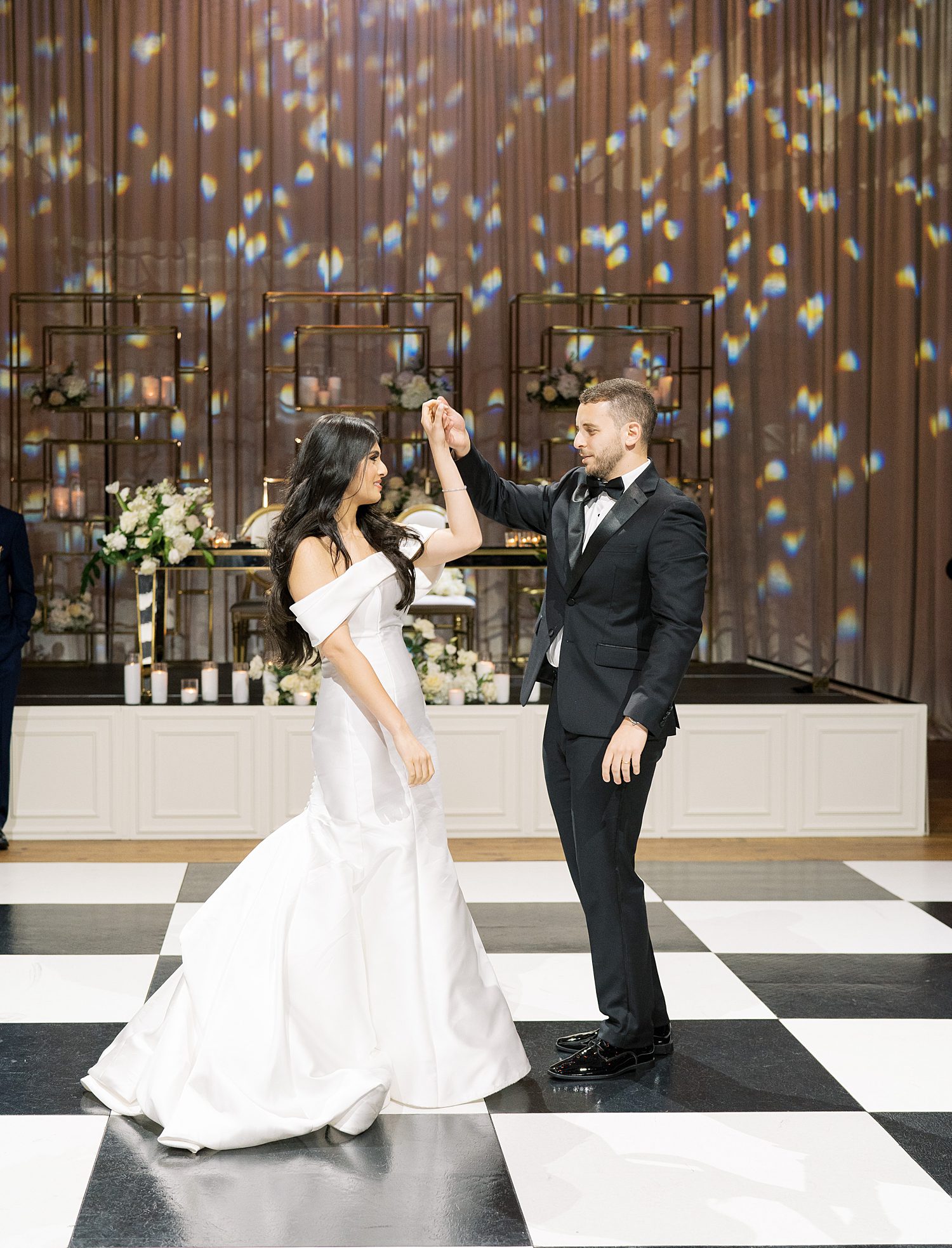 groom twirls bride on black and white dance floor at Armature Works