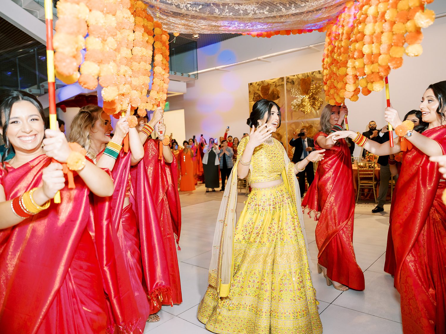 bride in yellow dress dances with women during  Mehndi Day in Tampa FL museum 