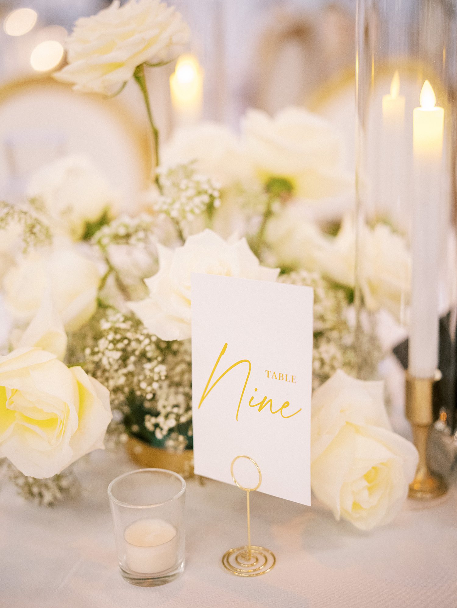 white rose centerpieces with candles and table numbers for traditional wedding reception at Armature Works 