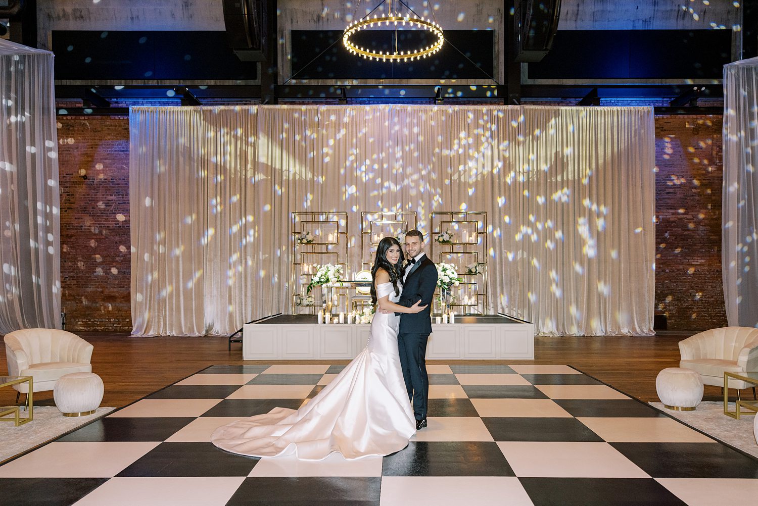bride and groom stand on black and white dance floor during traditional wedding reception at Armature Works