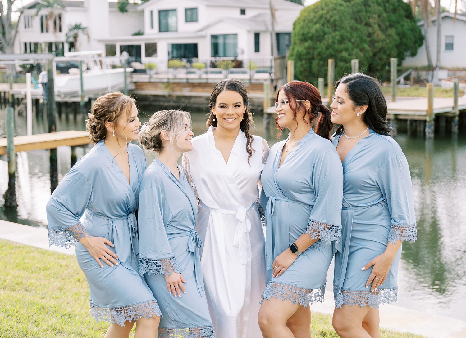 bride poses with bridesmaids in light bleu robes on morning of Tampa FL wedding day