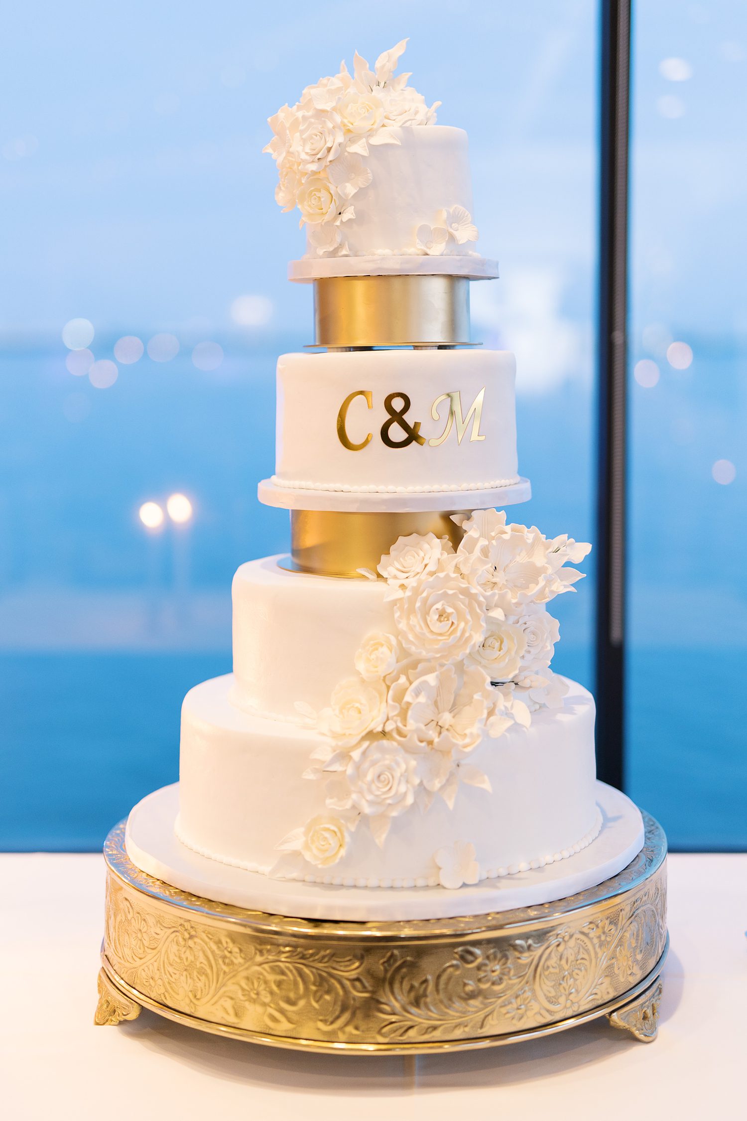 tiered wedding cake with gold and white floral accents 