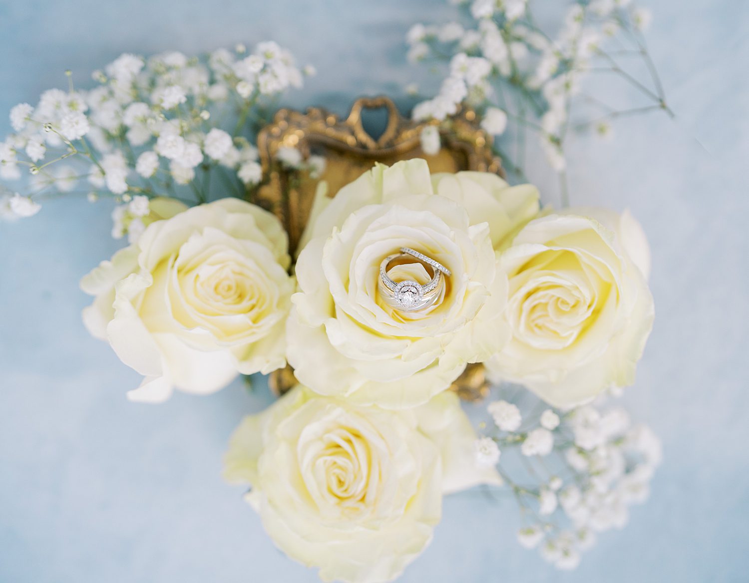 diamond ring rests in ivory roses on gold tray