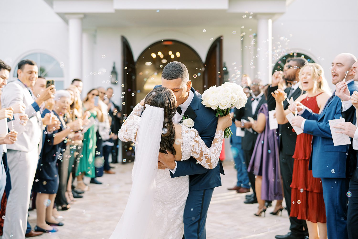 groom dips bride kissing her outside Harborside Chapel surrounded by guests