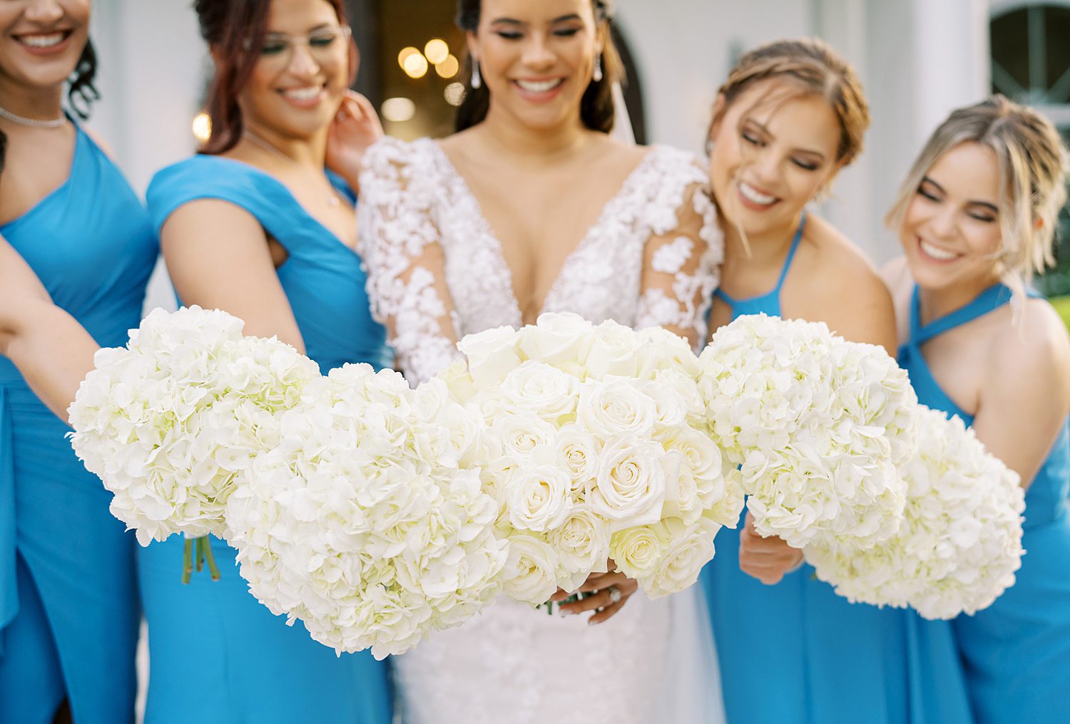 bride holds bouquet of ivory roses in blue gowns outside Harborside Chapel