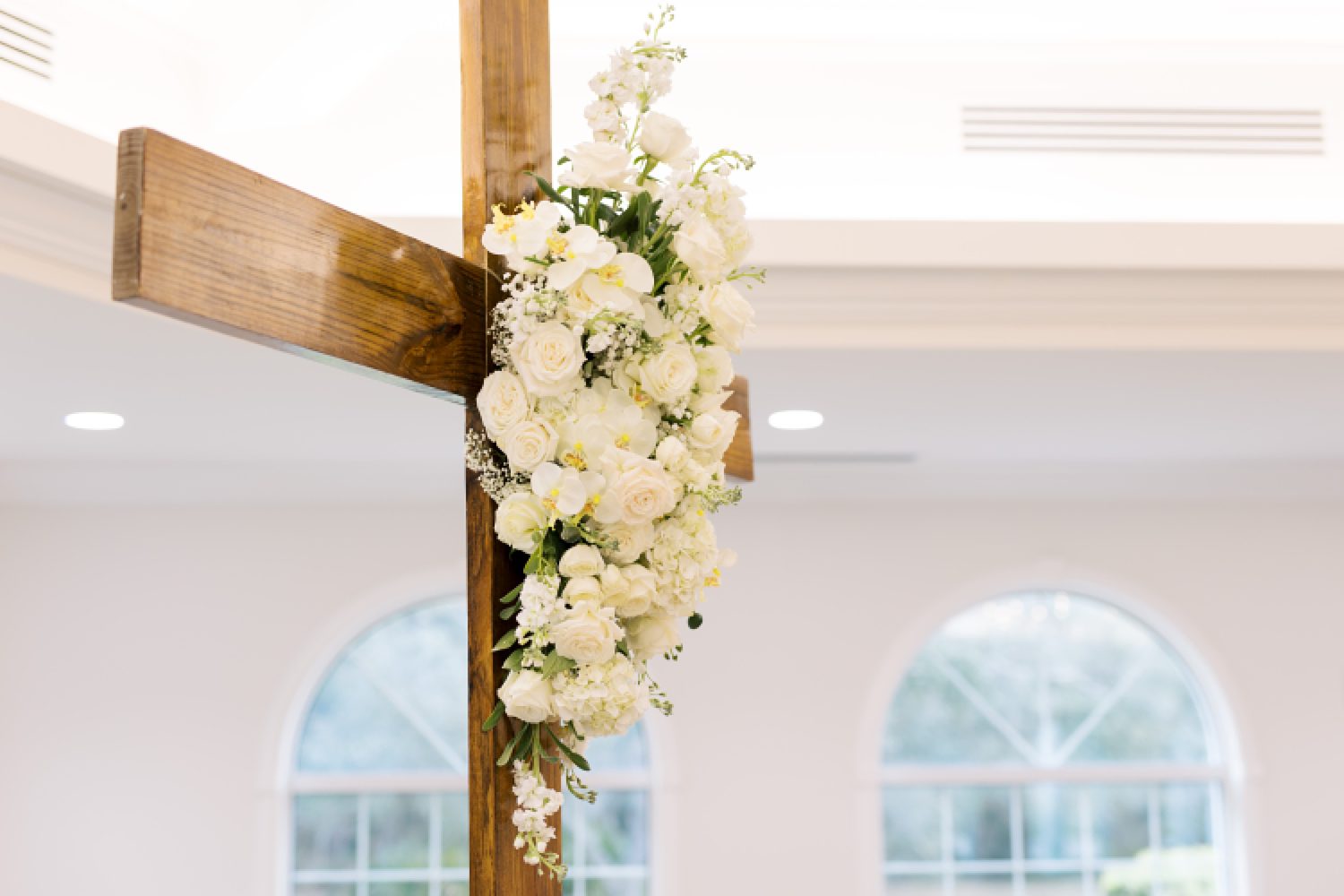 white rose bunch hangs on wooden cross inside Harborside Chapel in Tampa FL