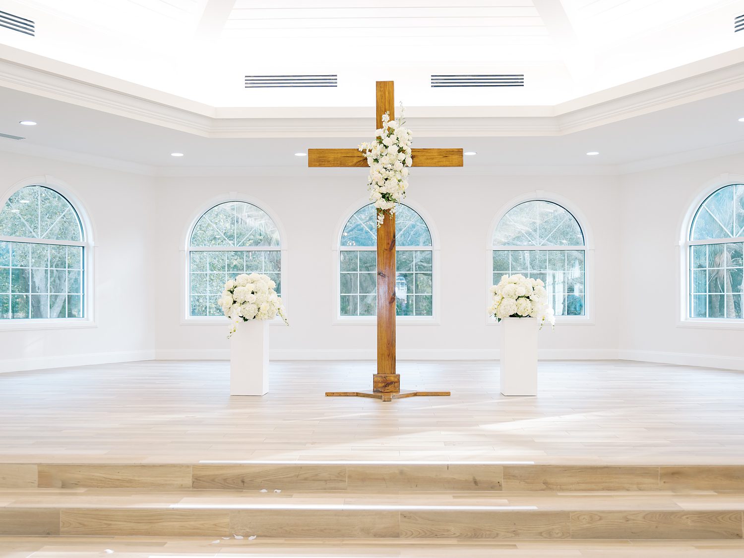 ceremony site with wooden cross and ivory flowers inside Harborside Chapel