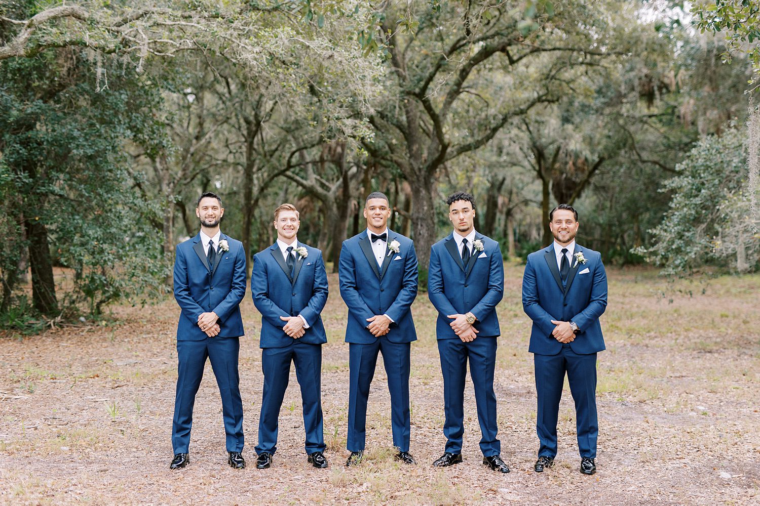 groom stands with groomsmen in navy suits outside the Rusty Pelican