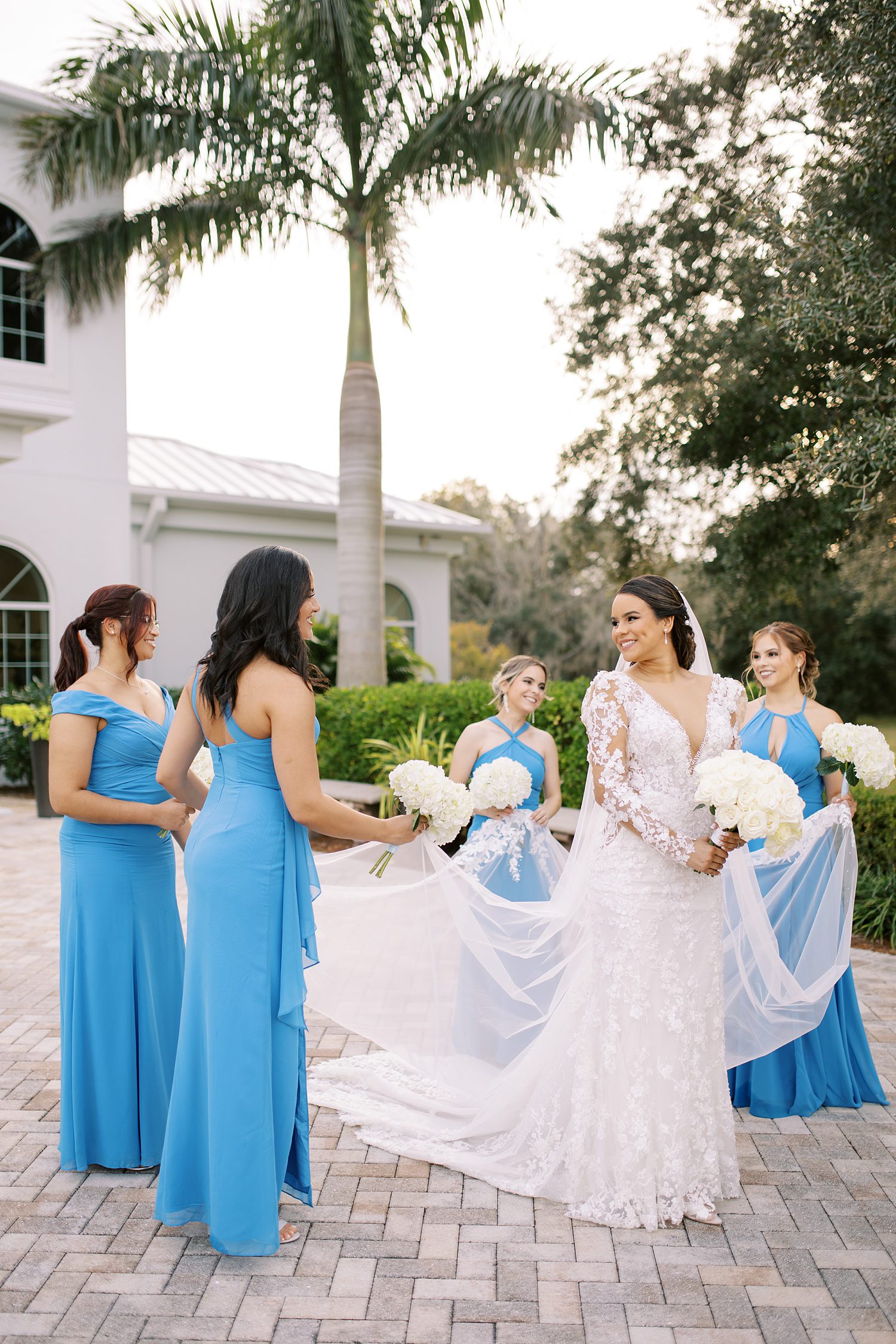 bride walks with bridesmaids in blue gowns and Ivory rose bouquets 