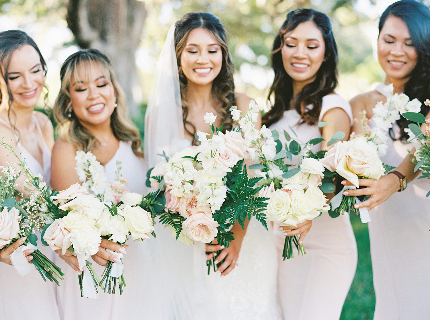 bride and bridesmaids hold bouquet of blush and ivory flowers for fall wedding at Tampa Yacht Club
