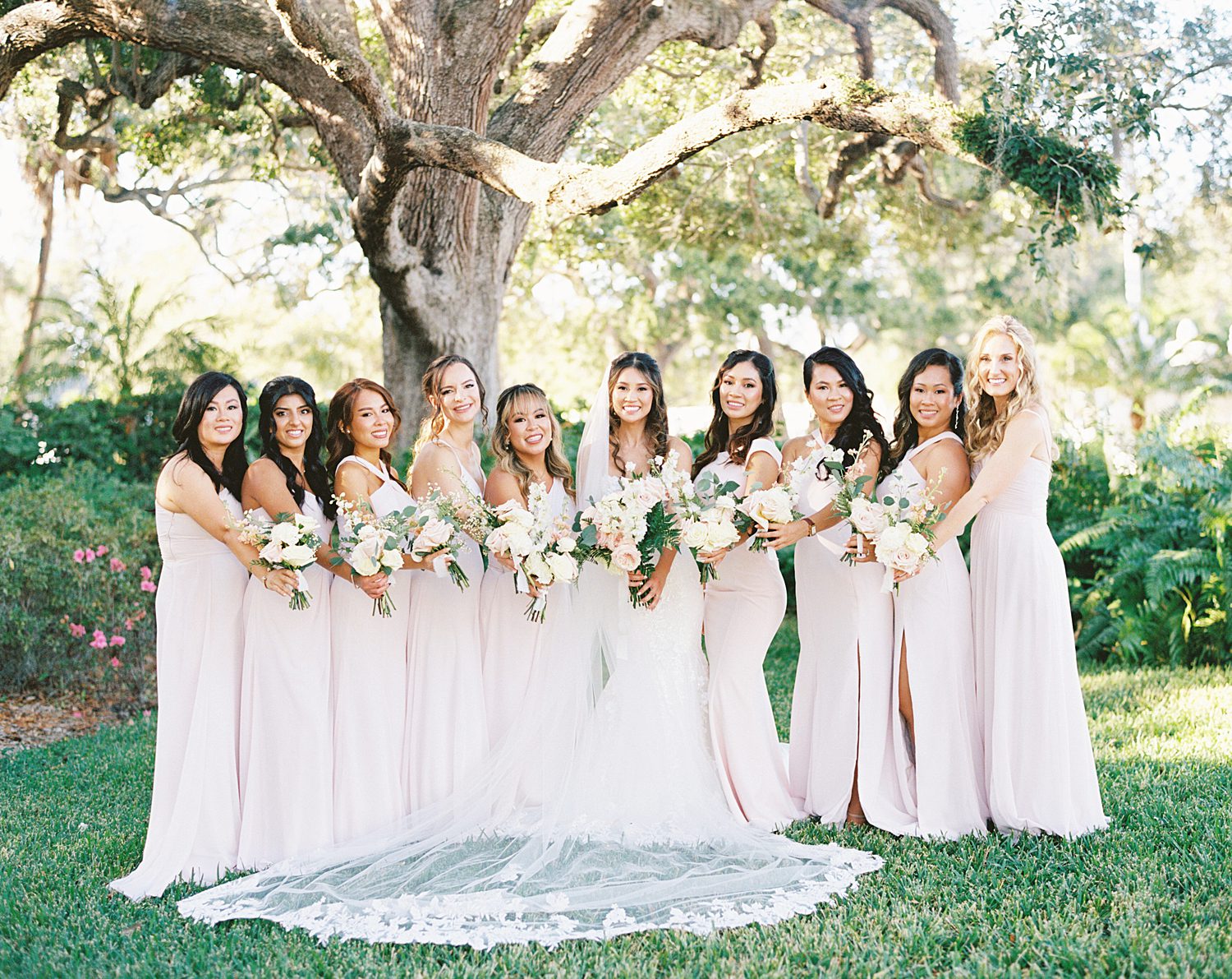 bride poses with bridesmaids in blush pink gowns and pastel bouquets at Tampa Yacht Club