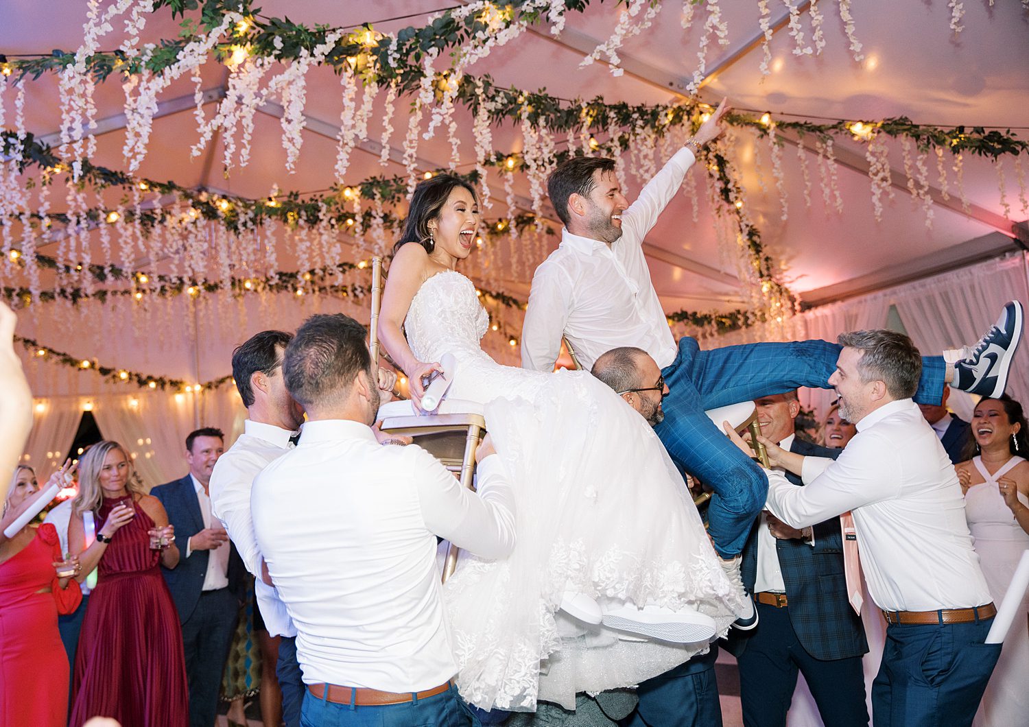 bride and groom cheer while guests lift them up on chairs during reception at Tampa Yacht Club