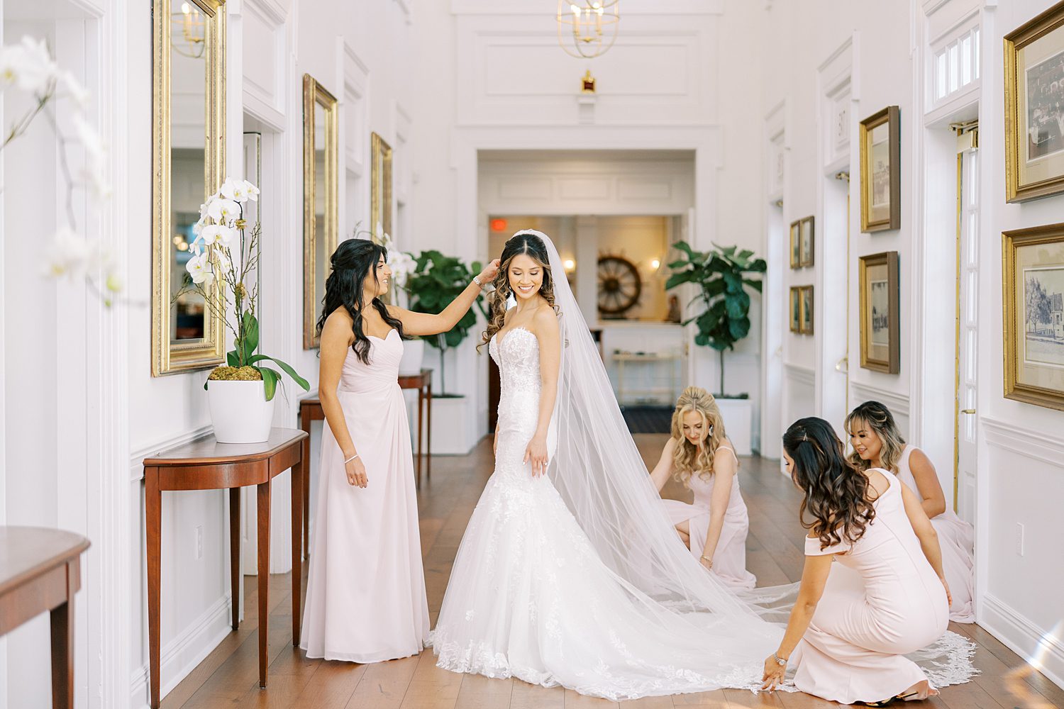 bridesmaids in blush gowns help bride with veil and dress trial at Tampa Yacht Club