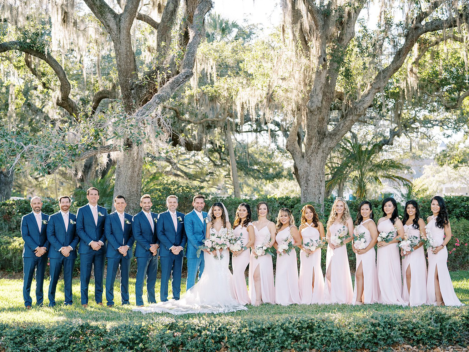 bride and groom pose with wedding party in blue suits and blush dresses at Tampa Yacht Club
