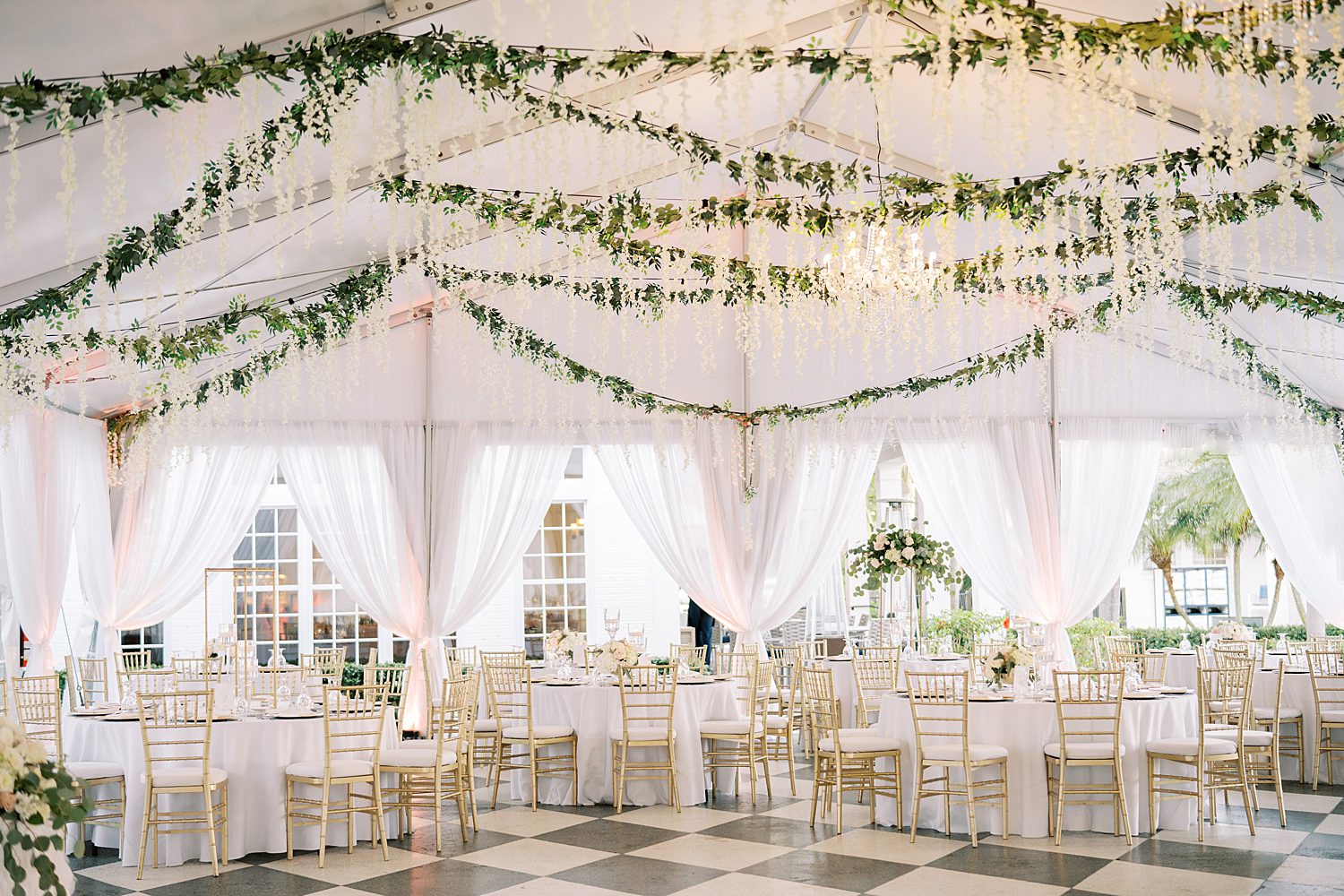 wedding reception at Tampa Yacht Club with black and white dance floor, greenery draped from ceiling, and white flowers 