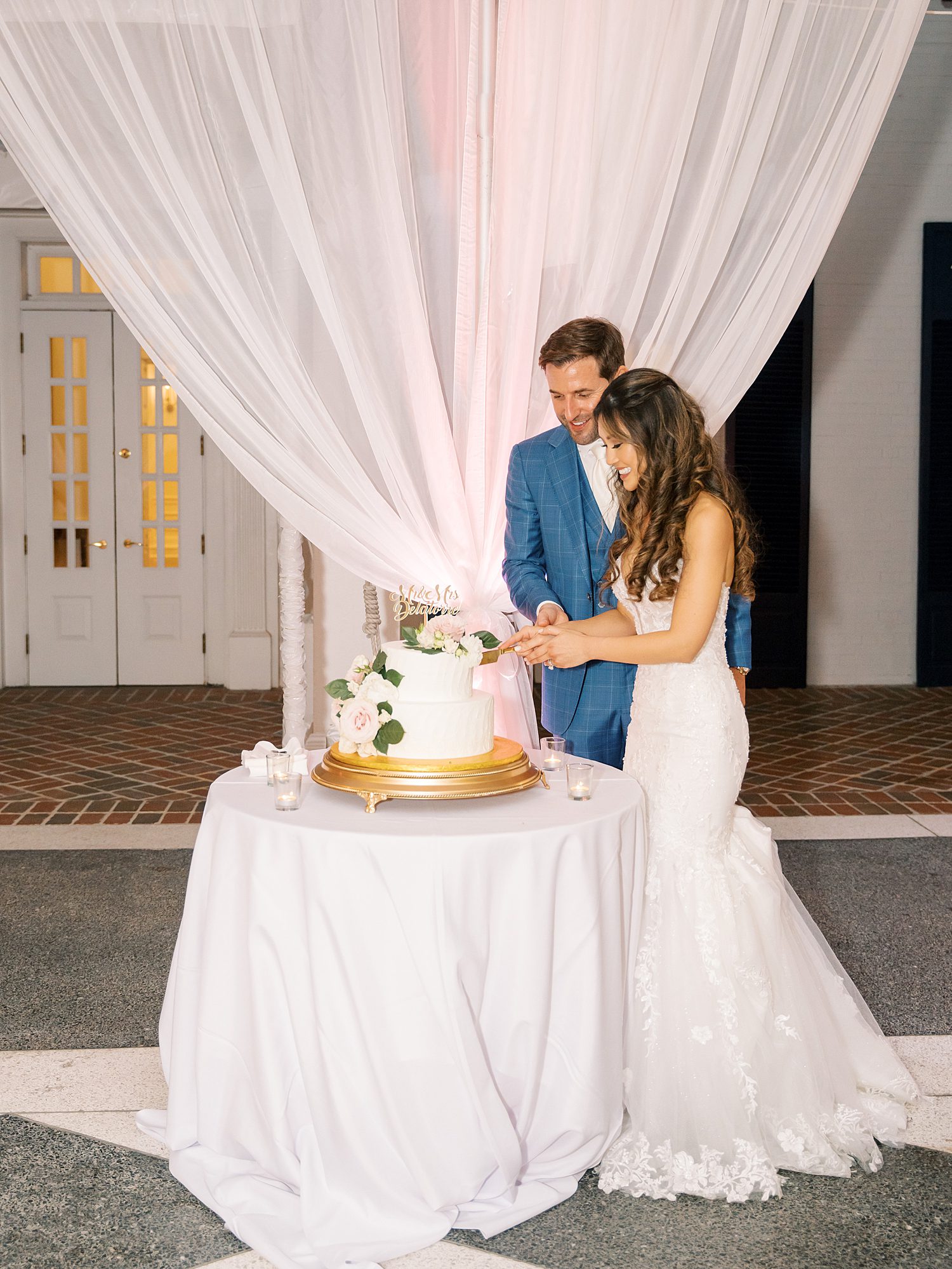newlyweds cut wedding cake during tented wedding reception at Tampa Yacht Club