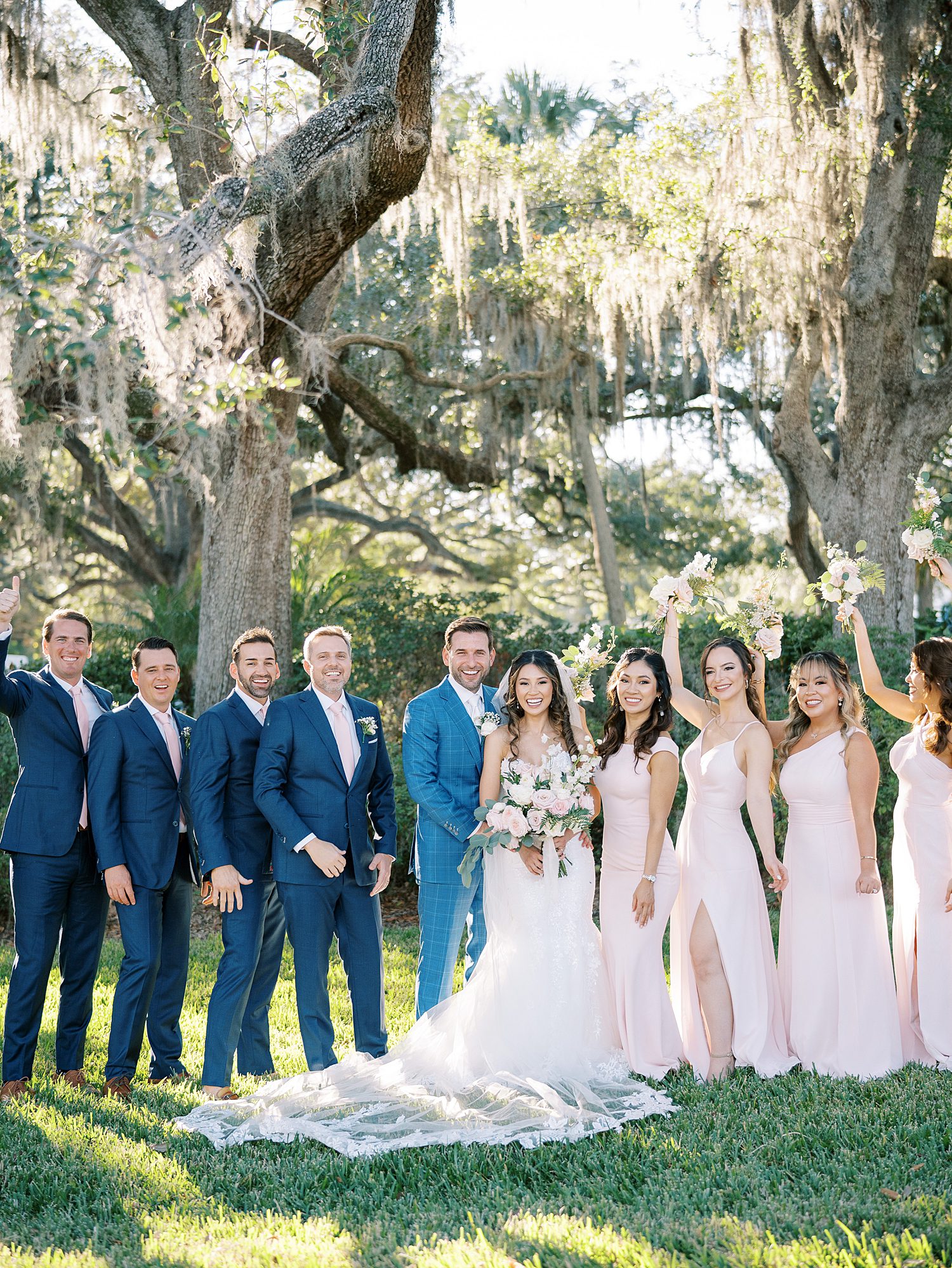 newlyweds pose with wedding party in blush dresses and navy suits 