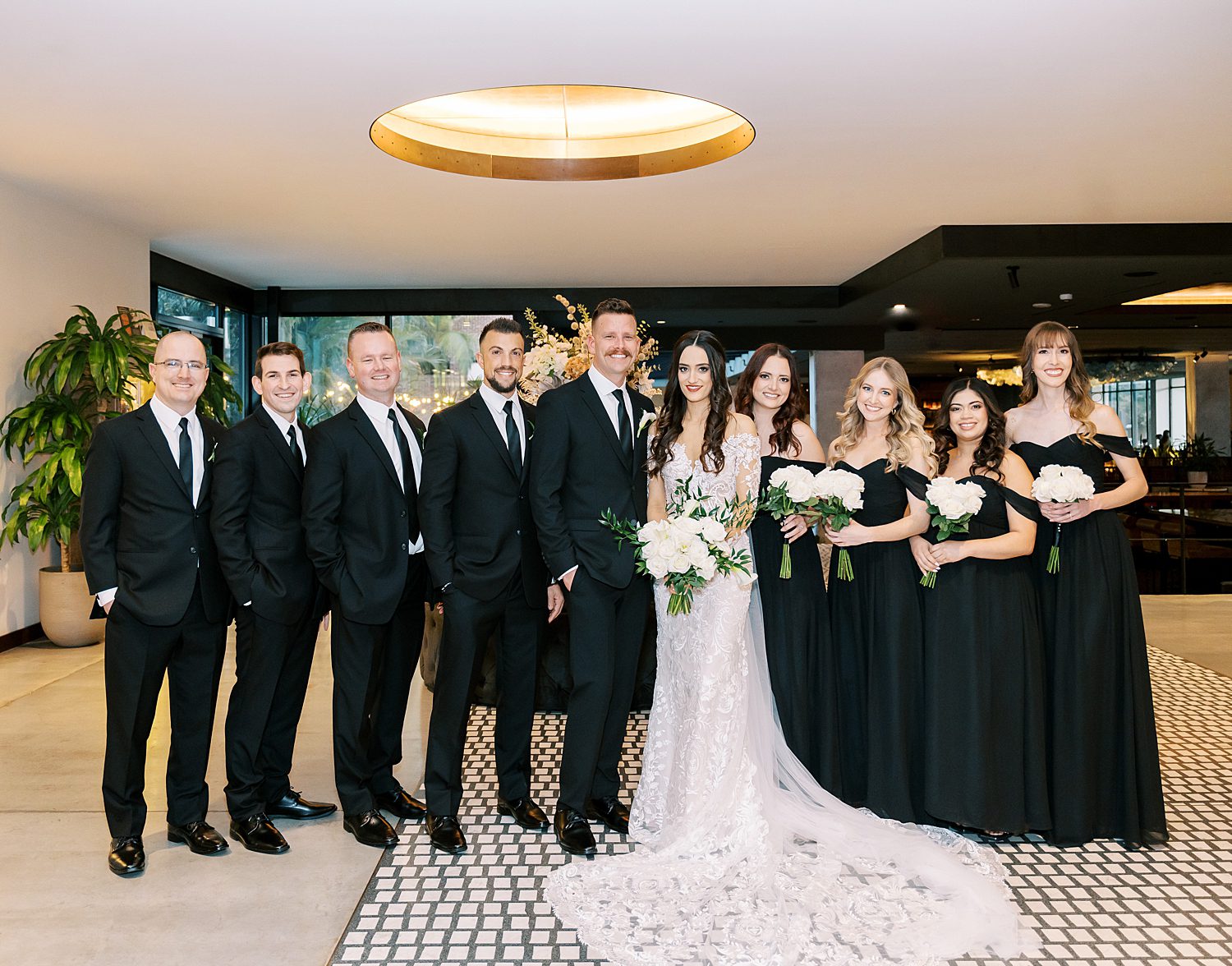 newlyweds pose with wedding party in all-black attire at the Hotel Haya