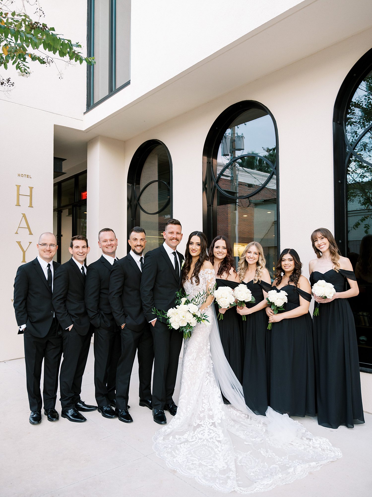 bride and groom stand with wedding party in all-black attire in Tampa FL