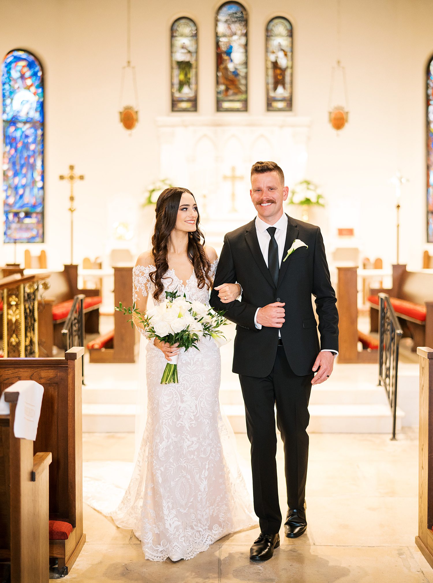 bride and groom smile walking up aisle at St. Andrews Episcopal Church in Tampa FL