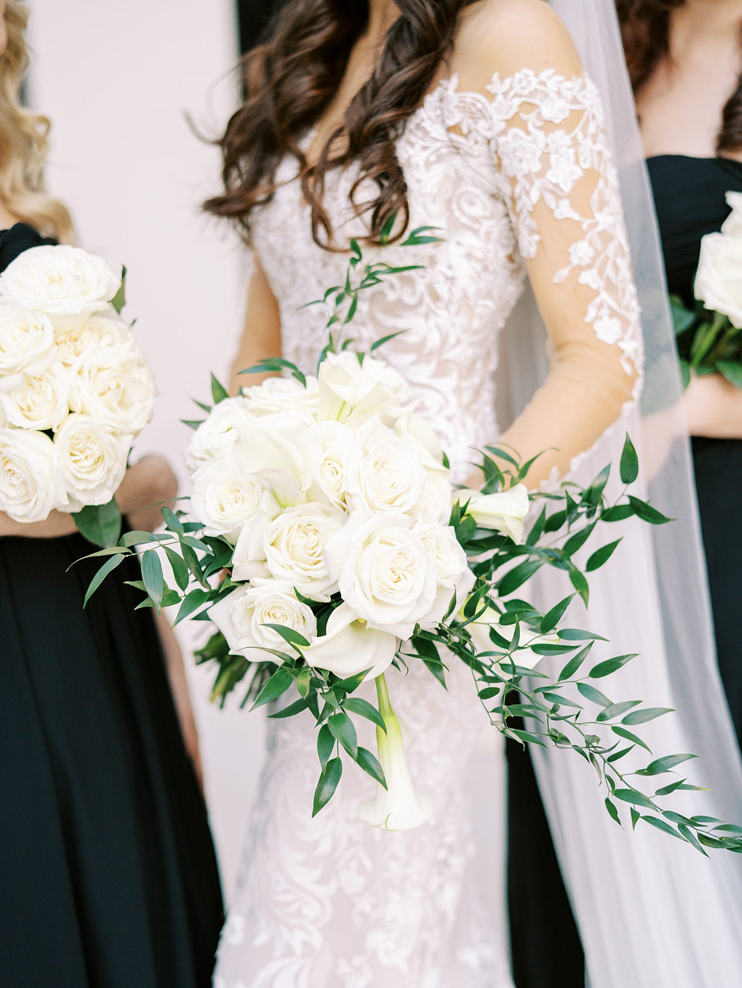 bride in wedding dress with lace sleeves holds all-white bouquet of flowers 