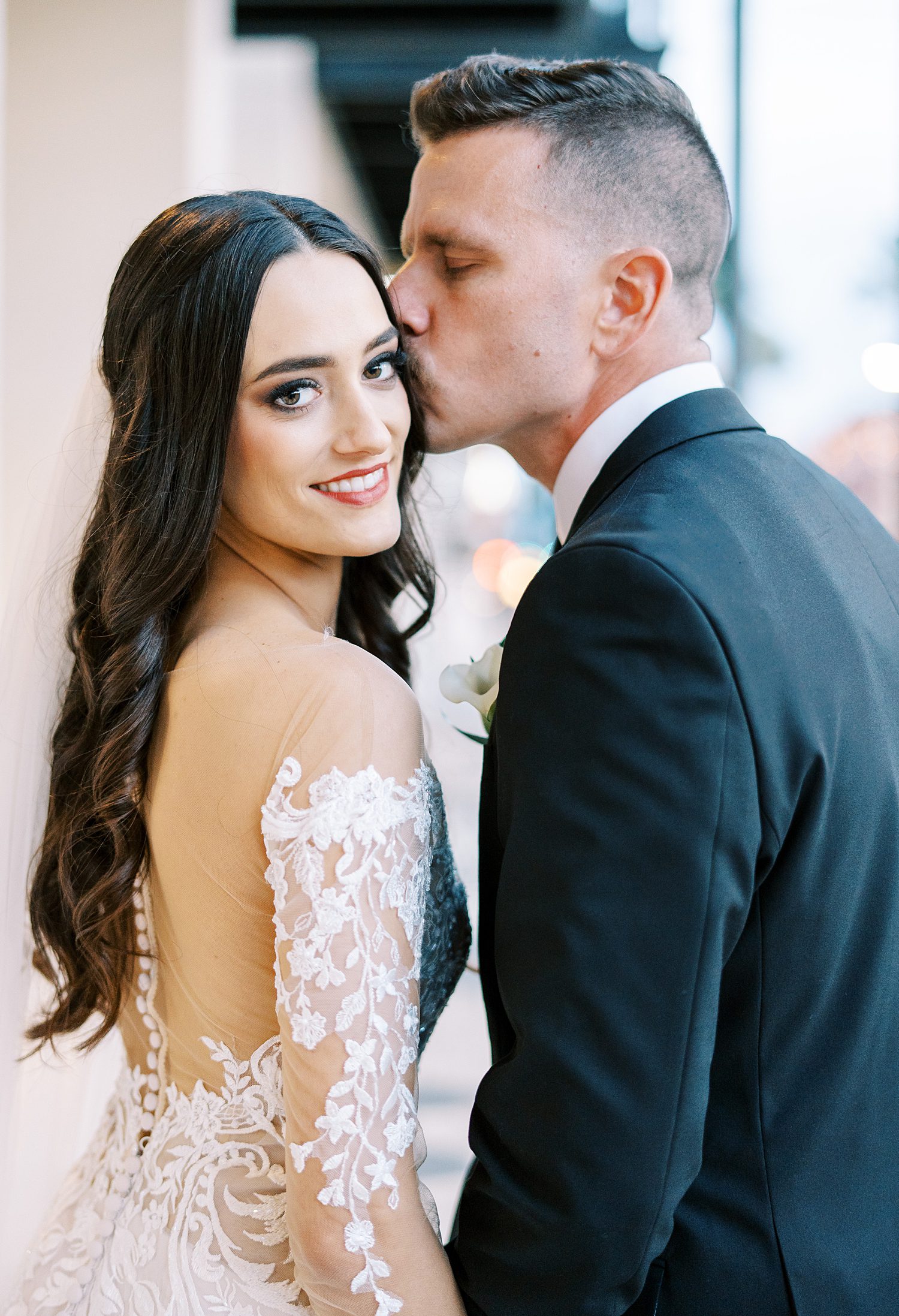 groom leans to kiss bride's forehead on Tampa FL sidewalk 